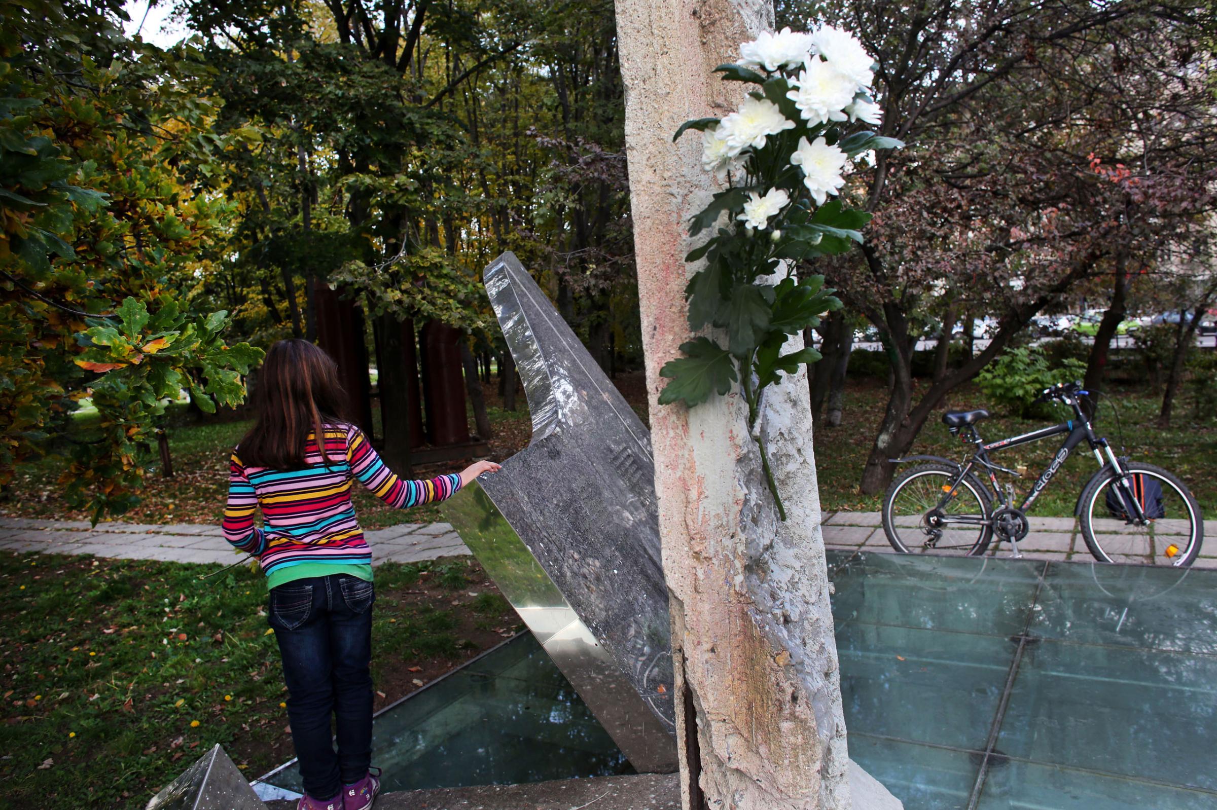 A child leans on a piece of the Berlin Wall on November 9th, 2014, the 25th anniversary of the fall of the wall. This piece was gifted to Bulgaria's capital Sofia in 2006. This photo is from a project that aims to gauge the state and effect of democracy in the former Soviet satellite nation Bulgaria, two and a half decades after the fall of the Berlin Wall. The story of democracy in Bulgaria at age 25 is a cautionary tale about transplanting one-size-fits-all Western values to a nation still undergoing social and economic upheaval. Bulgaria is still one of the poorest, most corrupt nations in the European Union, its post-1989 hopes wilted by political instability, high crime rates and skyrocketing inflation. While Bulgarians can now freely vote and protest without much threat to their freedom, their new oppressor is corruption - which is at a 15 year high, across political and civil sectors alike. The ennui is so casually etched on the passerby's face that it becomes routine - one that fits in sadly well against a startling backdrop of rotting architecture, joblessness, and a vast population decline. Despite what democracy has changed in Bulgaria, the daily struggles of its populace remain largely untouched, trapped in a post-communist time capsule.This project was supported by a grant from The Pulitzer Center on Crisis Reporting. Photo by: Yana PaskovaCopyright © Yana Paskova 2014