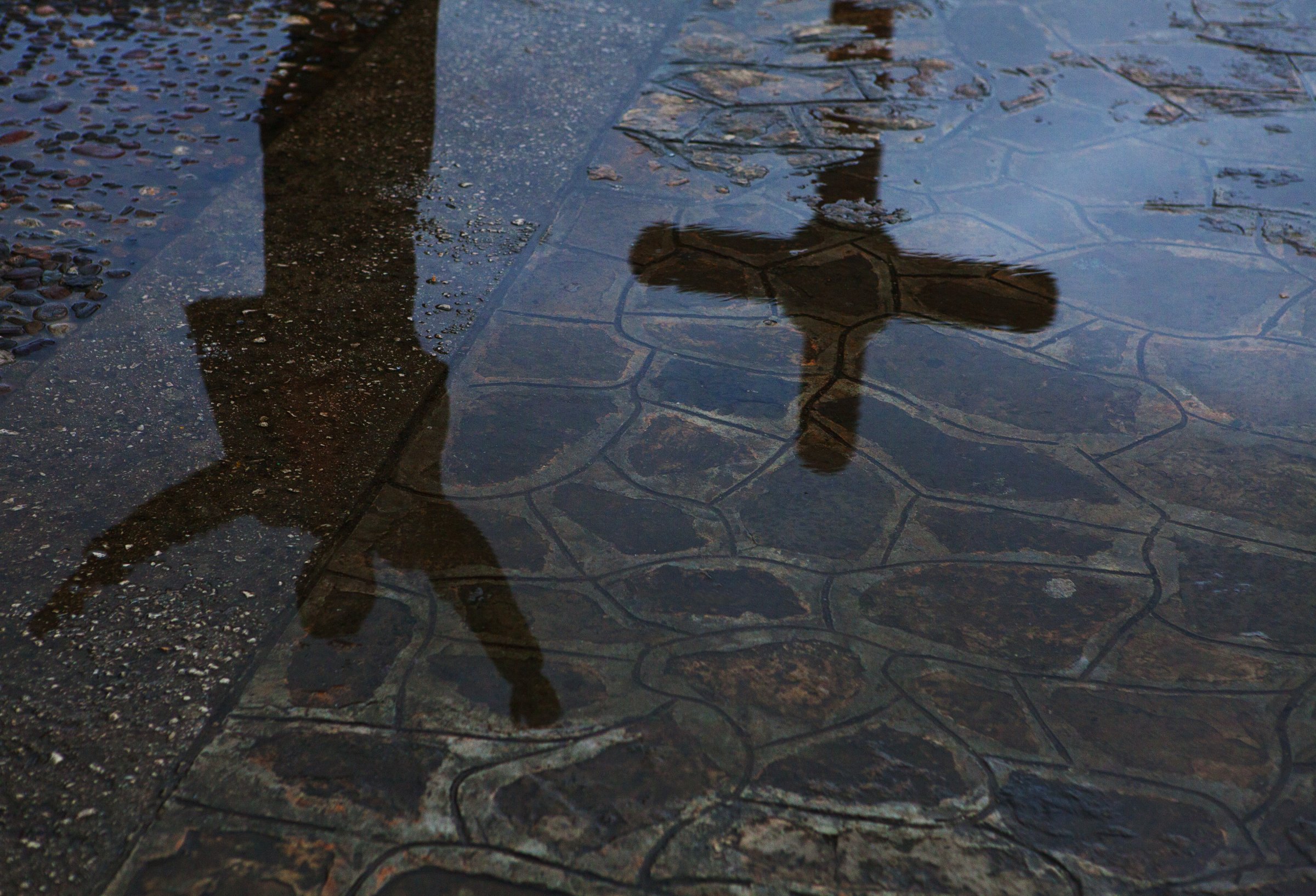 Reflection of man and crucifix in city puddle