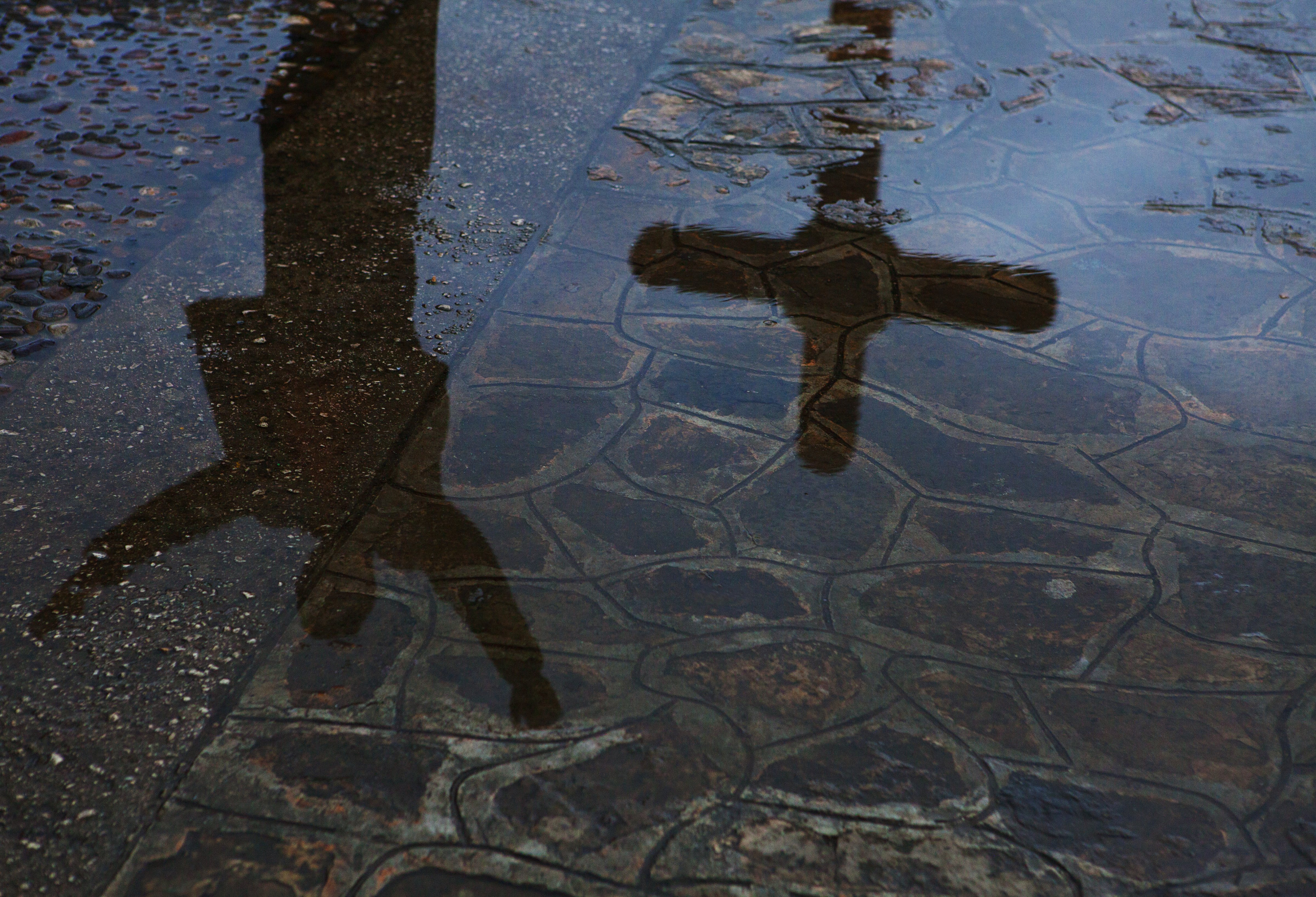 187138413Reflection of man and crucifix in city puddle