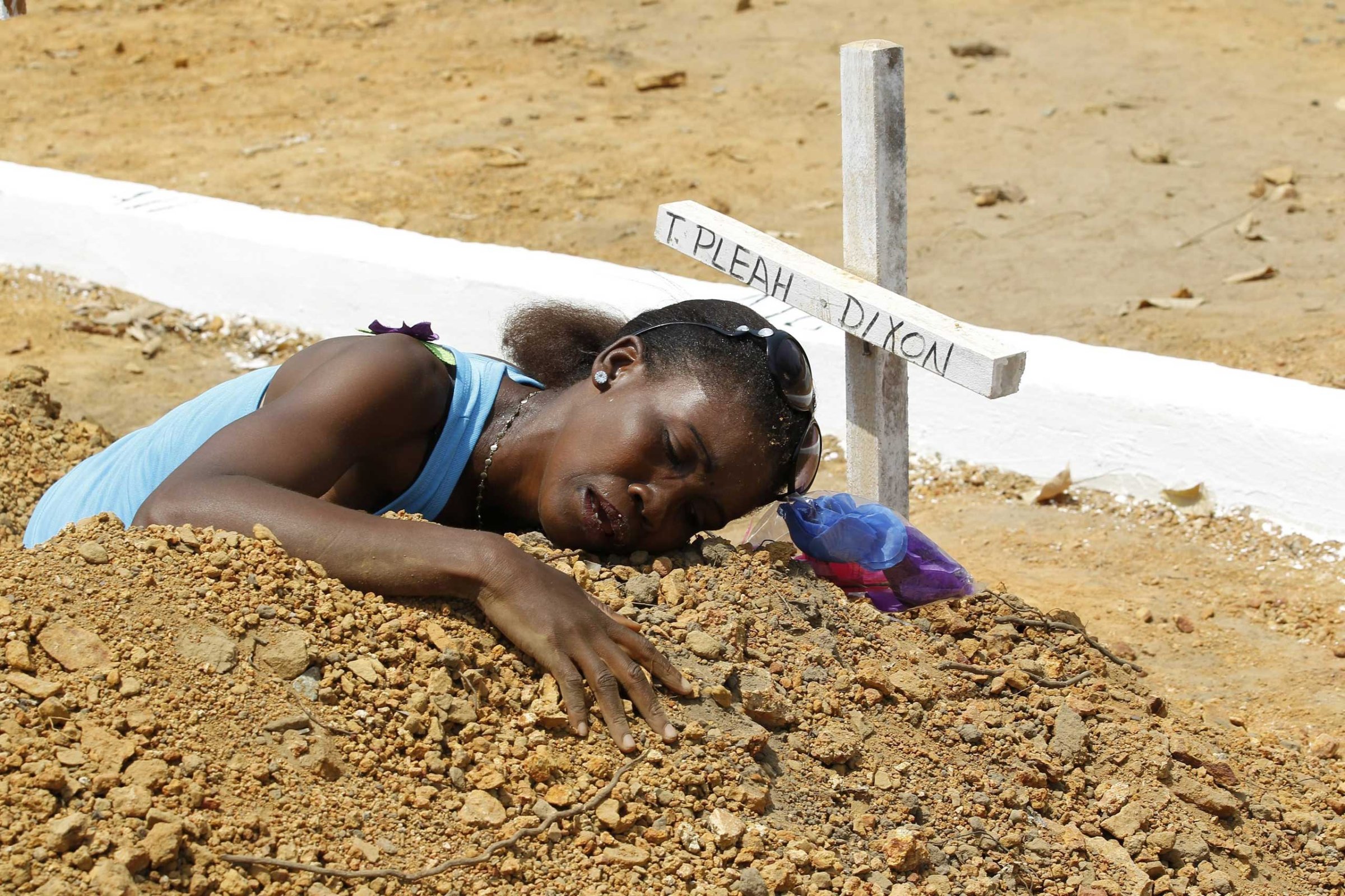 A woman mourns at the grave of her late brother at the National Cemetry on Disco Hill, Margibi County, Liberia, March 11, 2015.