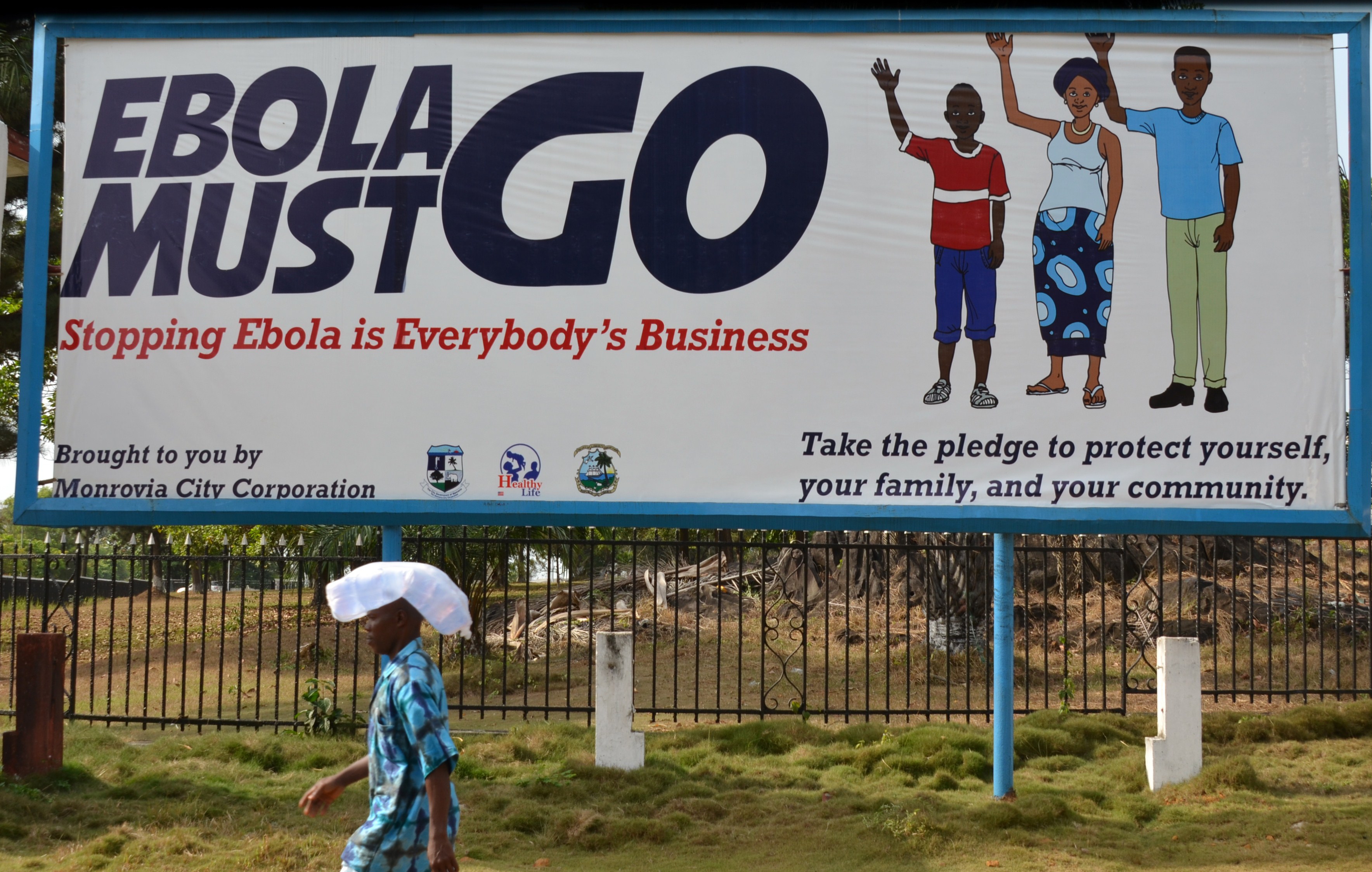 A man walks past an ebola campaign banner with the new slogan "Ebola Must GO" in Monrovia, Liberia on Feb. 23, 2015.