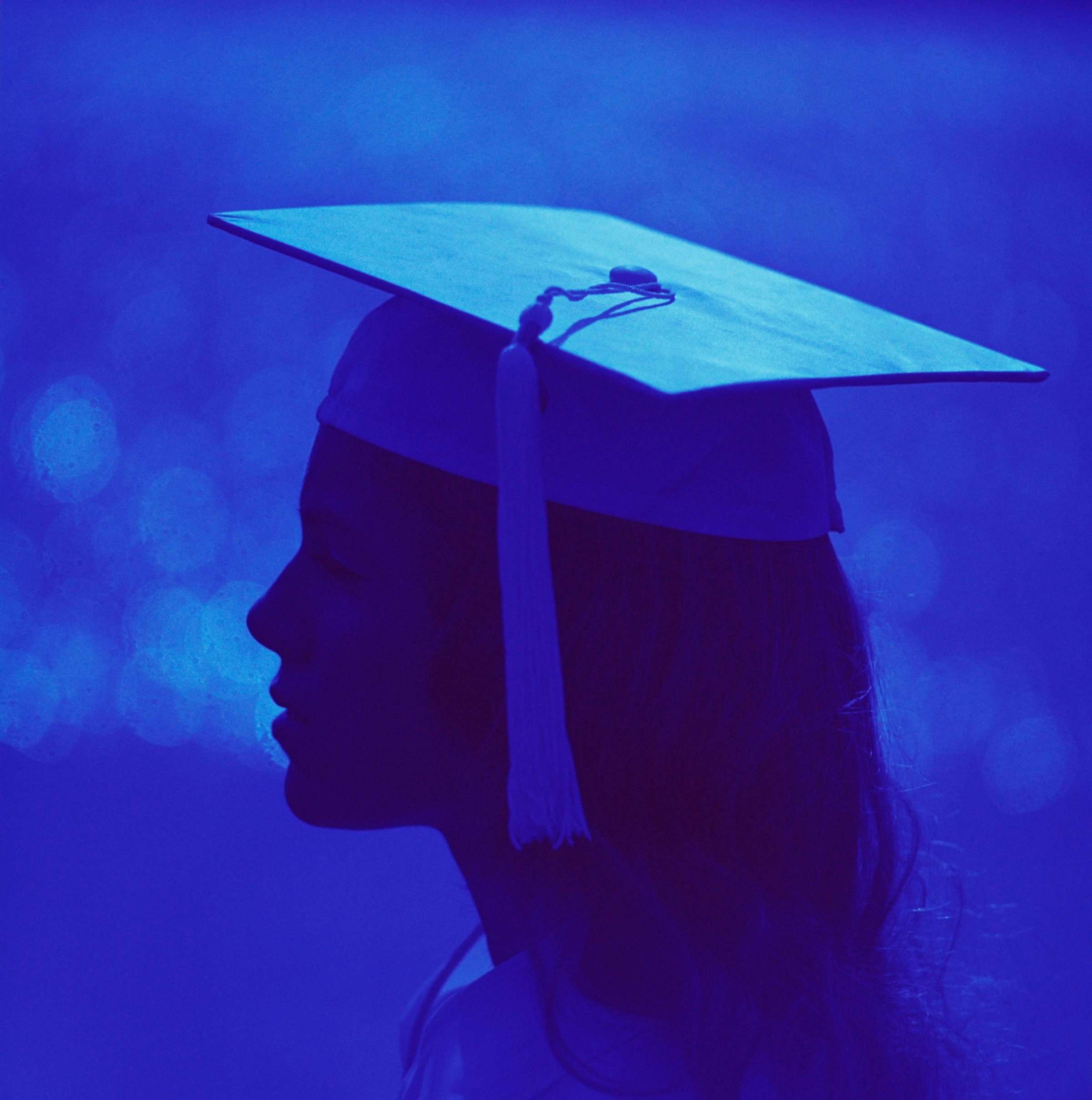 Silhouetted profile of woman wearing graduation cap