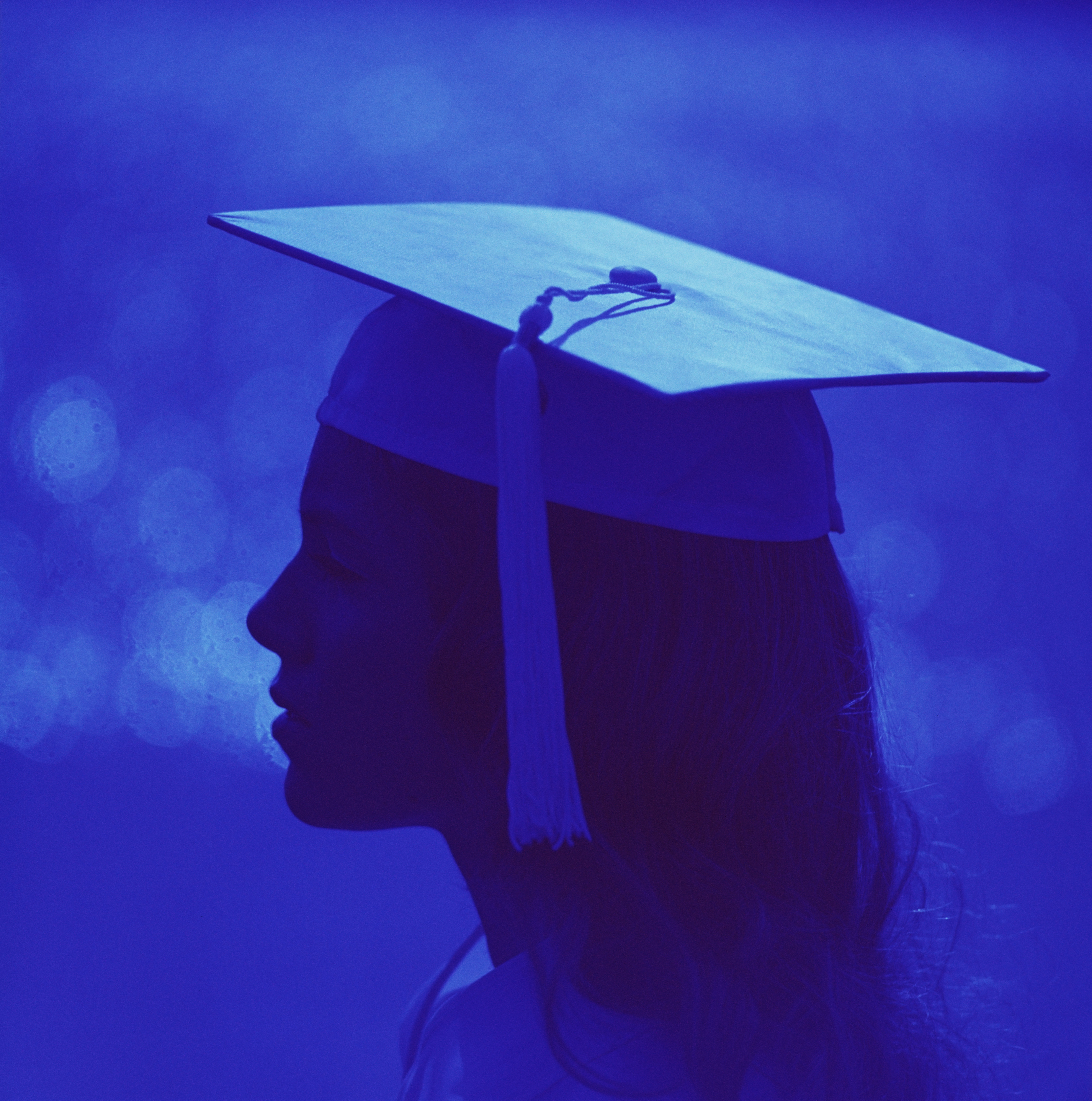 Silhouetted profile of woman wearing graduation cap