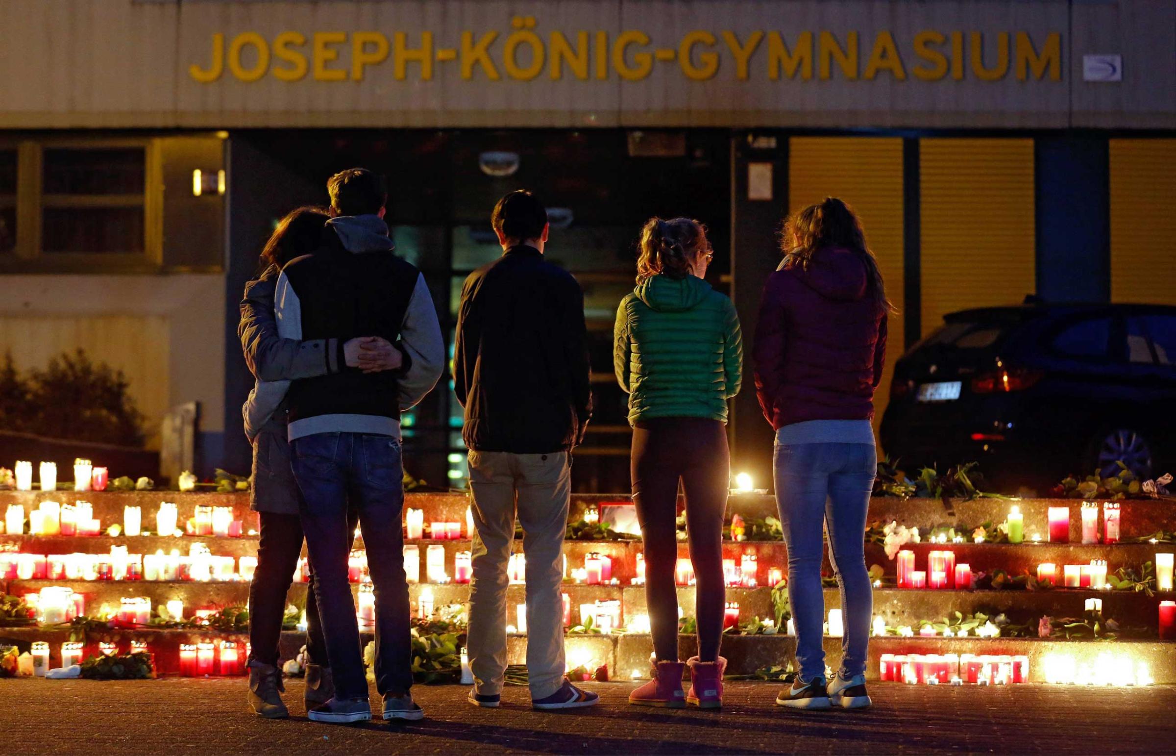 People stand in front of candles and flowers placed in front of the Joseph-Koenig-Gymnasium in Haltern, Germany, March 24, 2015.