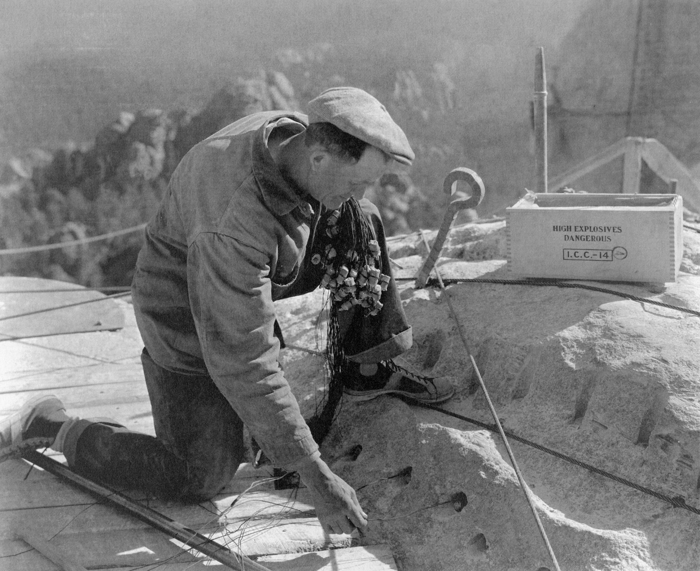 A powderman positions dynamite charges used to sculpt Mount Rushmore, c. 1930s.