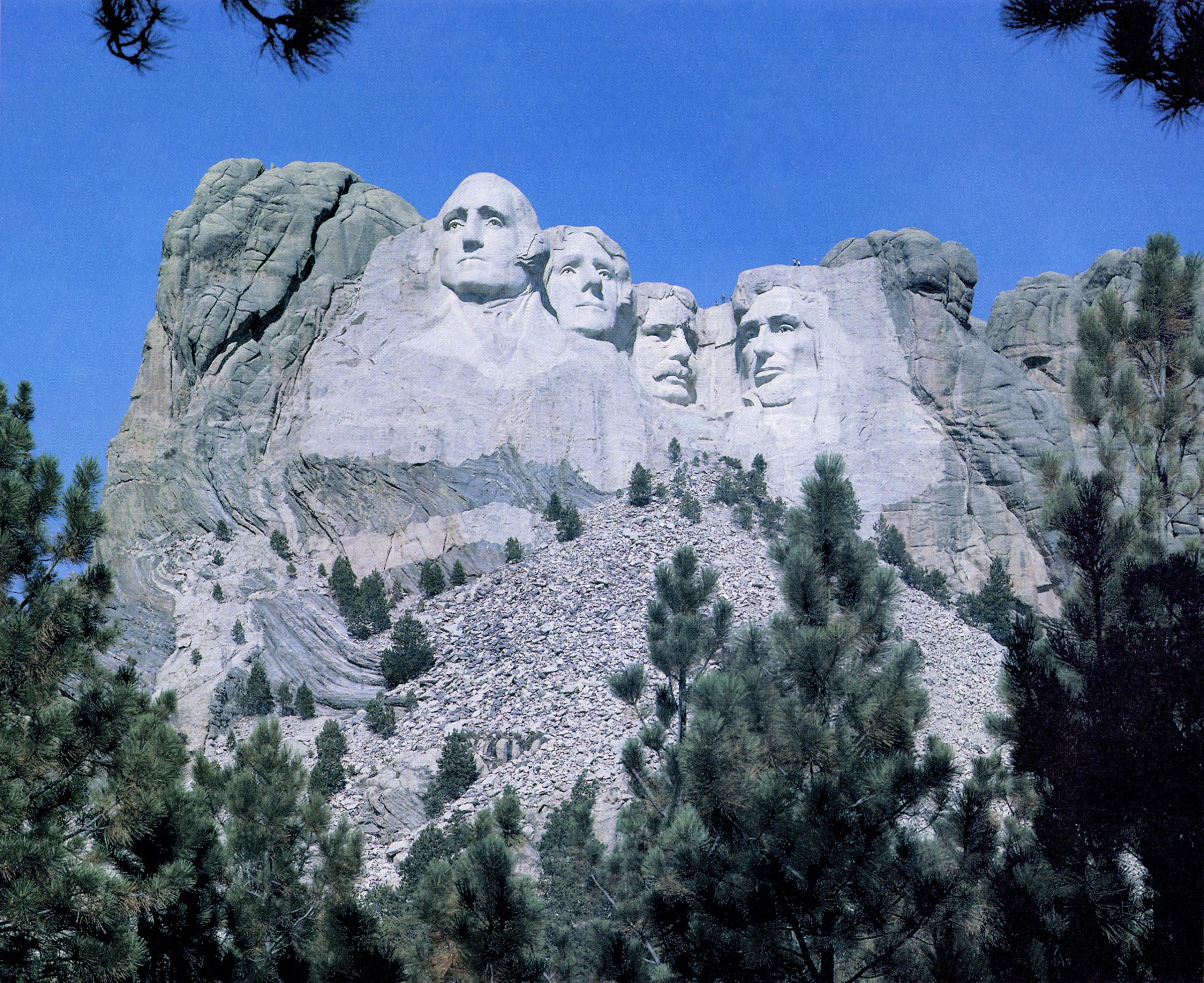 Mount Rushmore, as it appears today, with visitors climbing atop the monument.