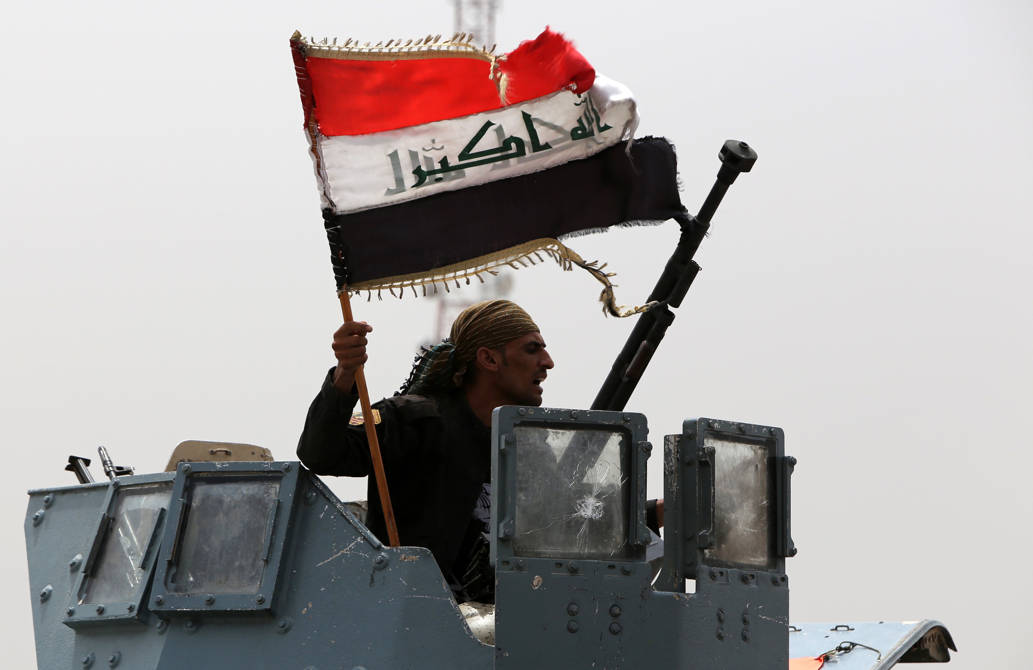 A member of the Iraqi antiterrorism forces waves the national flag in celebration after securing a checkpoint from Sunni militants in the village of Badriyah, west of the Iraqi city of Mosul, on Aug. 19, 2014 (Ahmad Al-Rubaye—AFP/Getty Images)