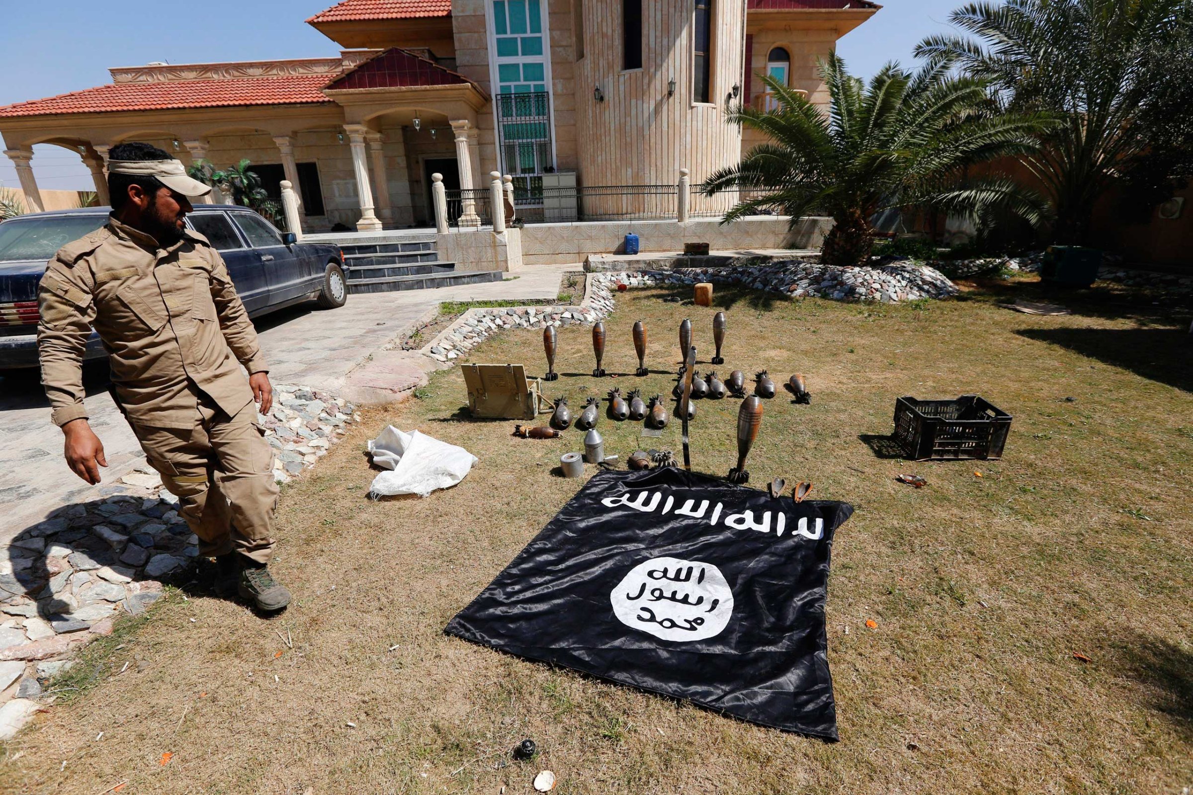 A Sunni fighter who has joined Shi'ite militia groups known collectively as Hashid Shaabi (Popular Mobilization), allied with Iraqi forces against the Islamic State, looks at an Islamic State flag and ammunition displayed in al-Alam Salahuddin province, March 15, 2015.