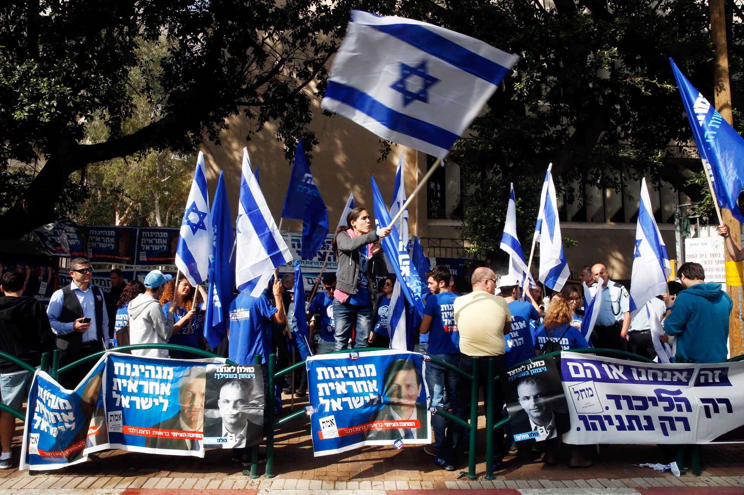 A woman waves an Israeli national flag outside a polling station in Tel Aviv, March 17, 2015.