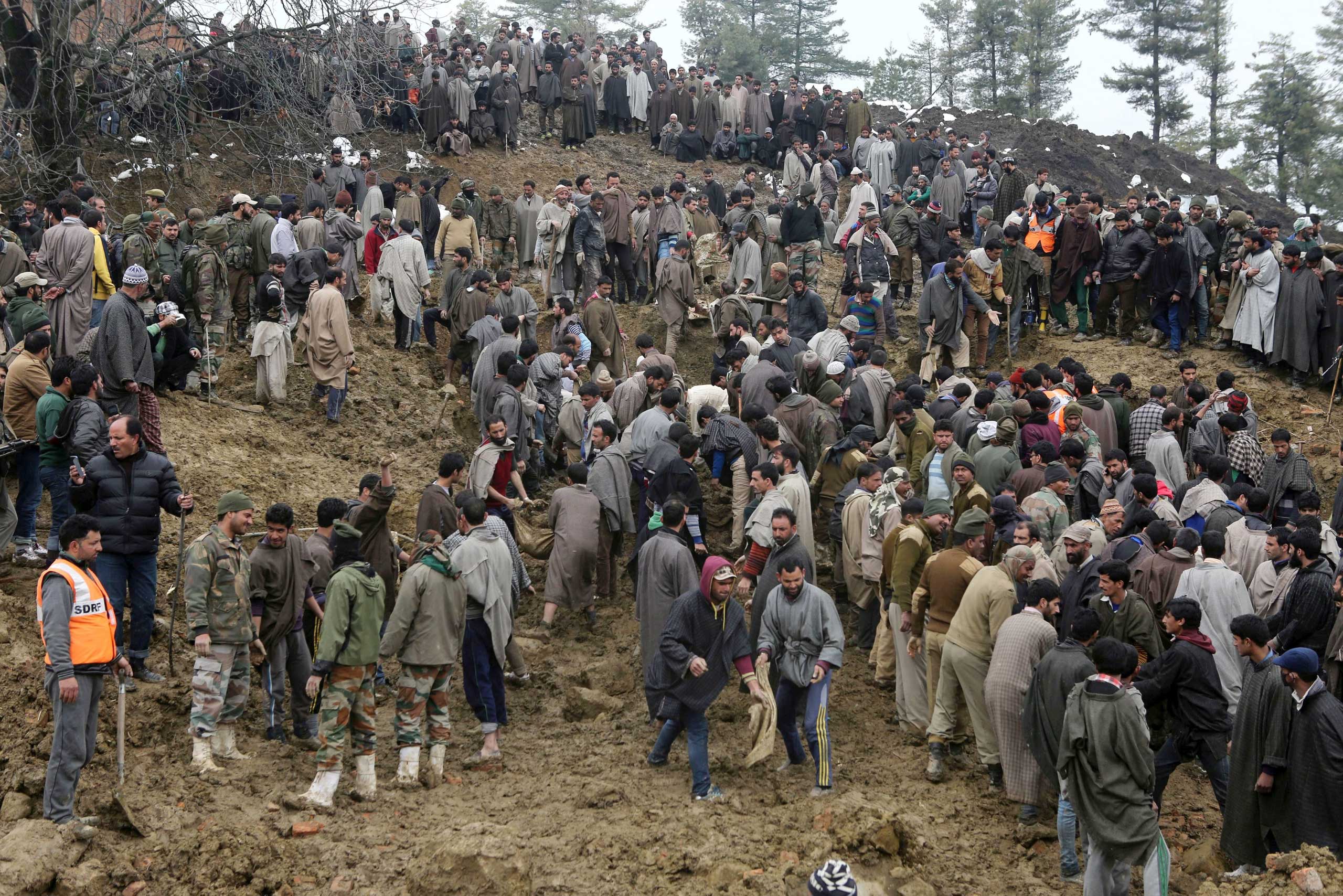 Kashmiri villagers look for missing residents following a landslide due to heavy rainfall in the village of Laden on March 30, 2015.