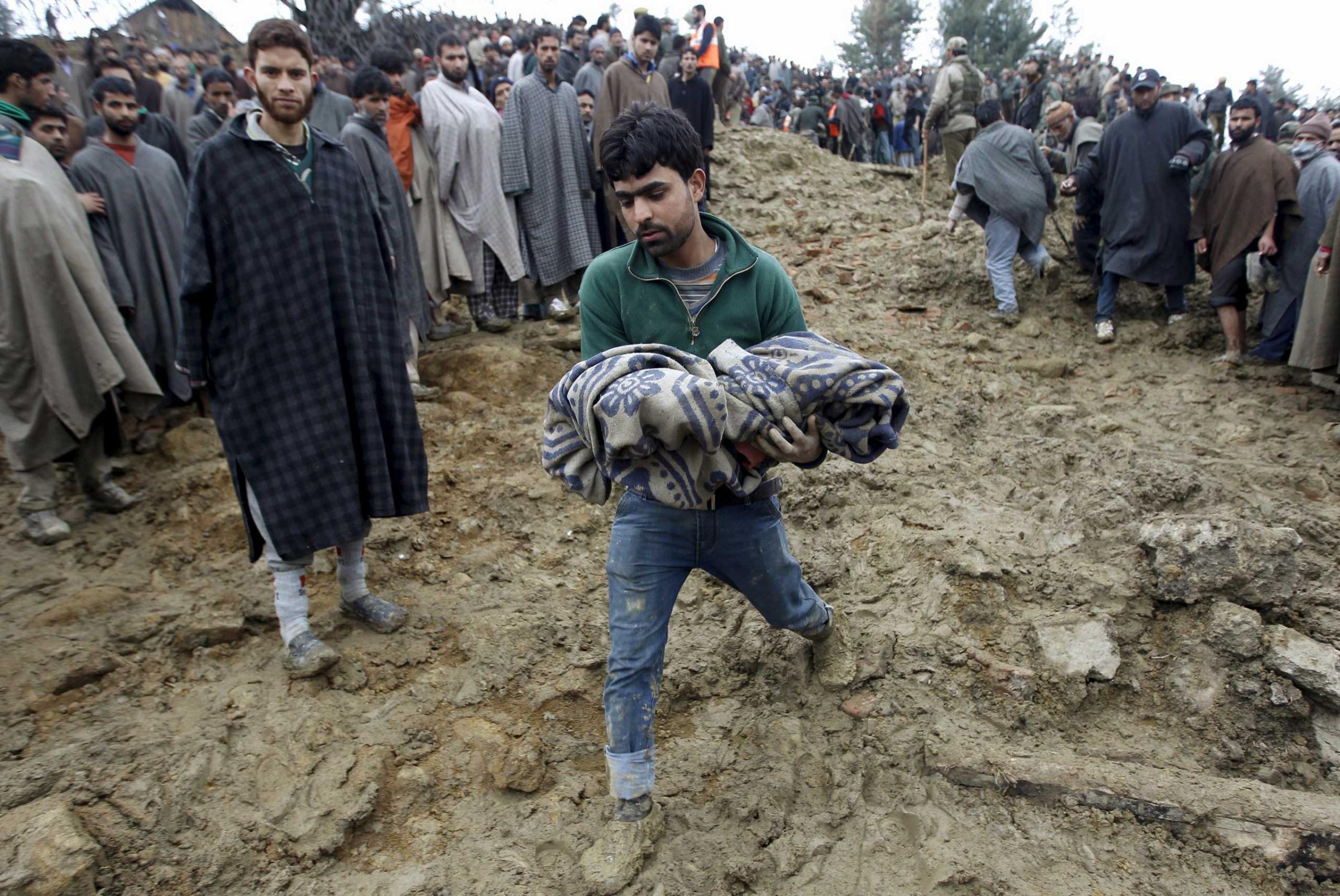 A Kashmiri man in the village of Laden carries the body of a child after it was pulled out from the rubble after a hillside collapsed onto a house on March 30, 2015.