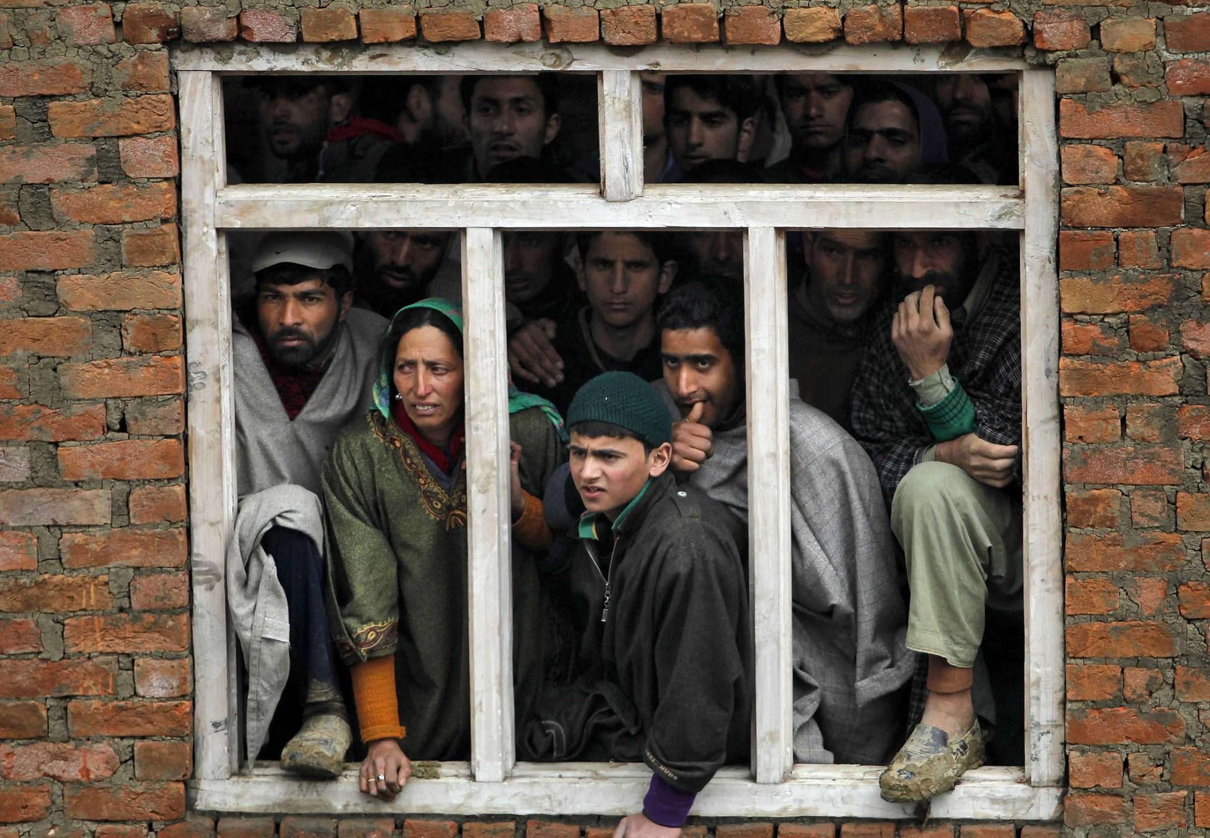 Kashmiri villagers watch the rescue operation at the site of a damaged home after a hillside collapsed onto it in the village of Laden on March 30, 2015.