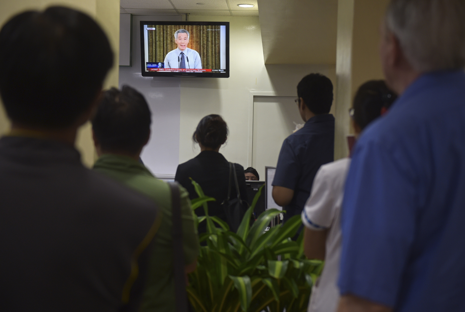 A live broadcast by Singaporean Prime Minister Lee Hsien Loong on the death of his father is watched in a reception area at a hospital where the city-state's first Prime Minister Lee Kuan Yew passed away on March 23, 2015, in Singapore (Joseph Nair — AP)
