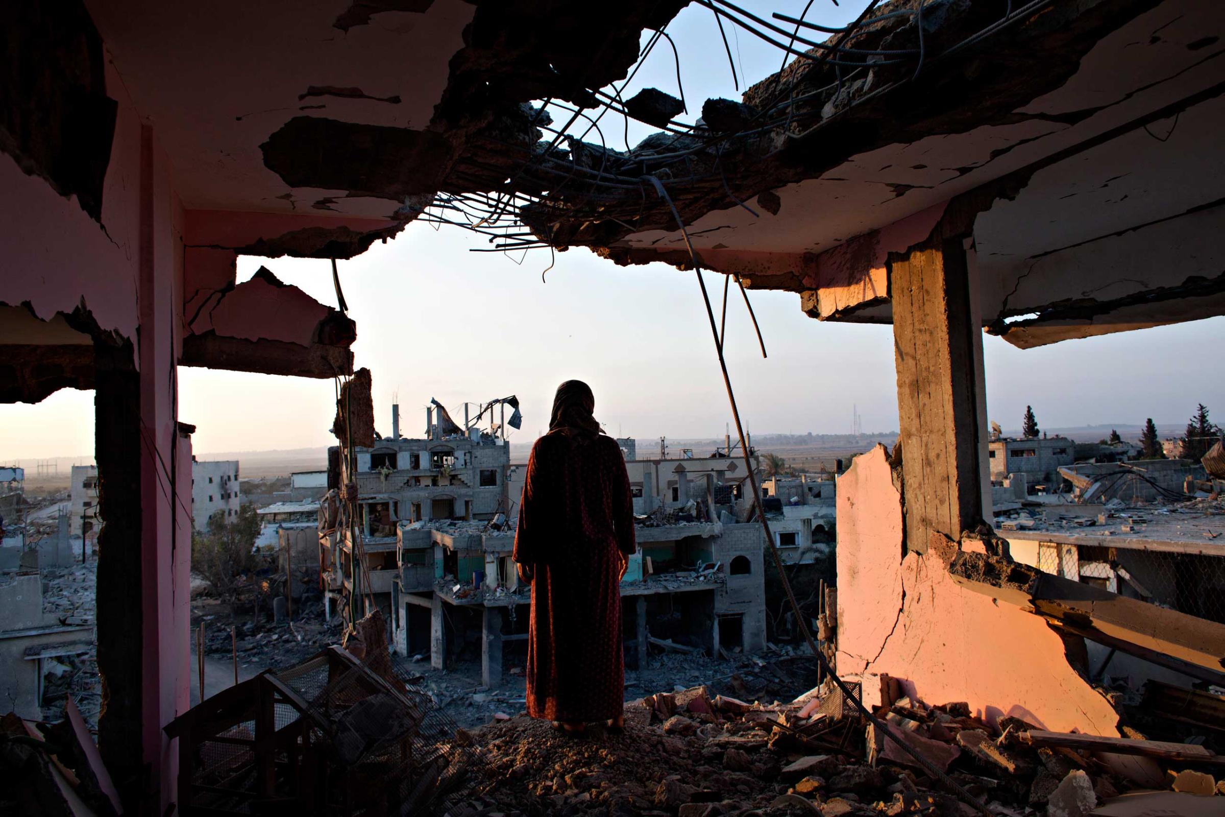 Hidya Atash stands on the top floor of her home as she overlooks the destruction in Shujayea in Gaza at dawn Aug. 8, 2014.