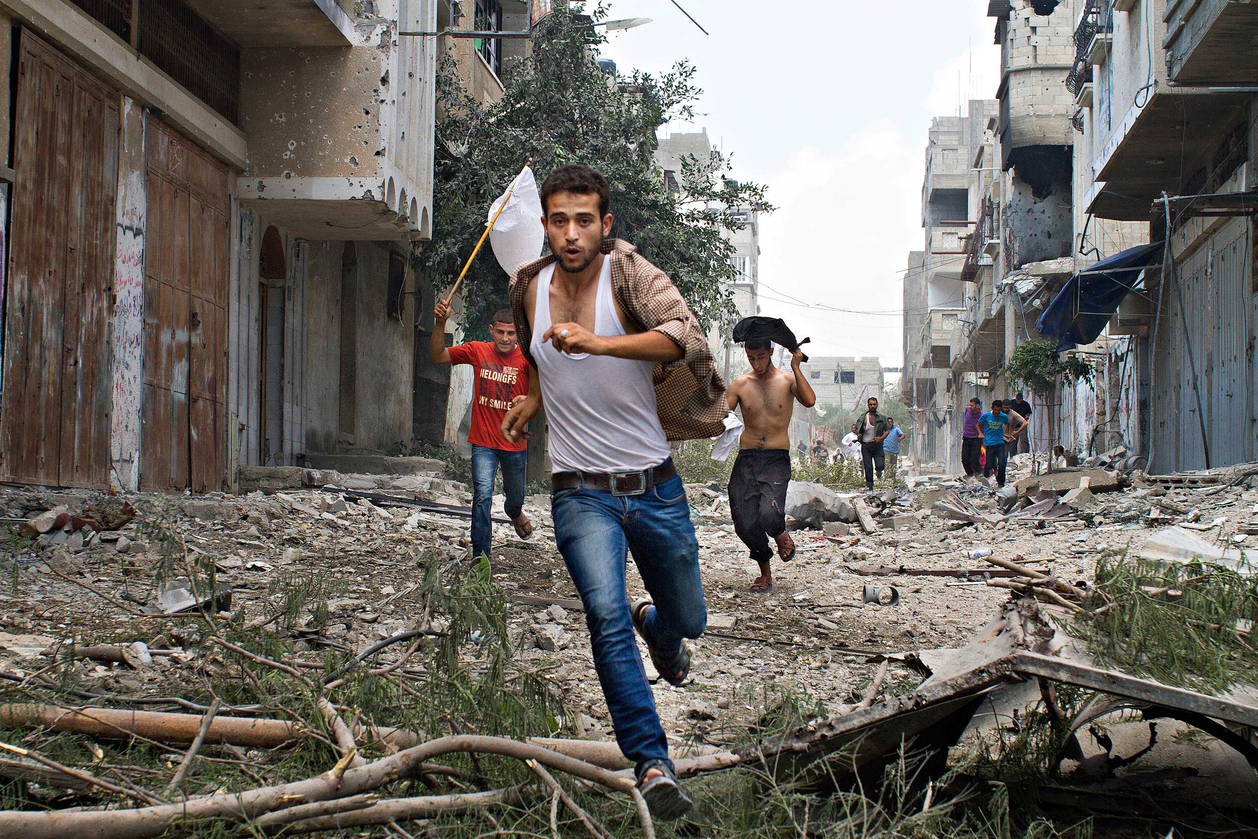 Palestinian men run with a white flag in the Shejaia neighborhood, which was heavily shelled by Israel during fighting, in Gaza City July 20, 2014.