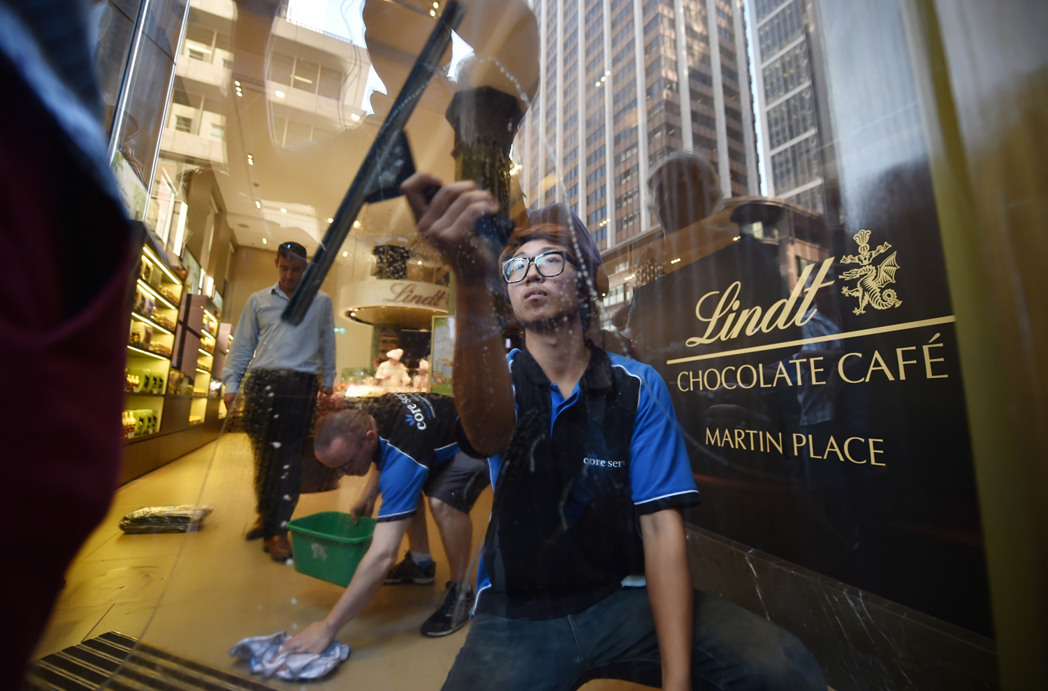 A staff member cleans the front door windows ahead of the re-opening of the Lindt Cafe at Martin Place in Sydney on March 20, 2015. (Peter Parks — AFP/Getty Images)