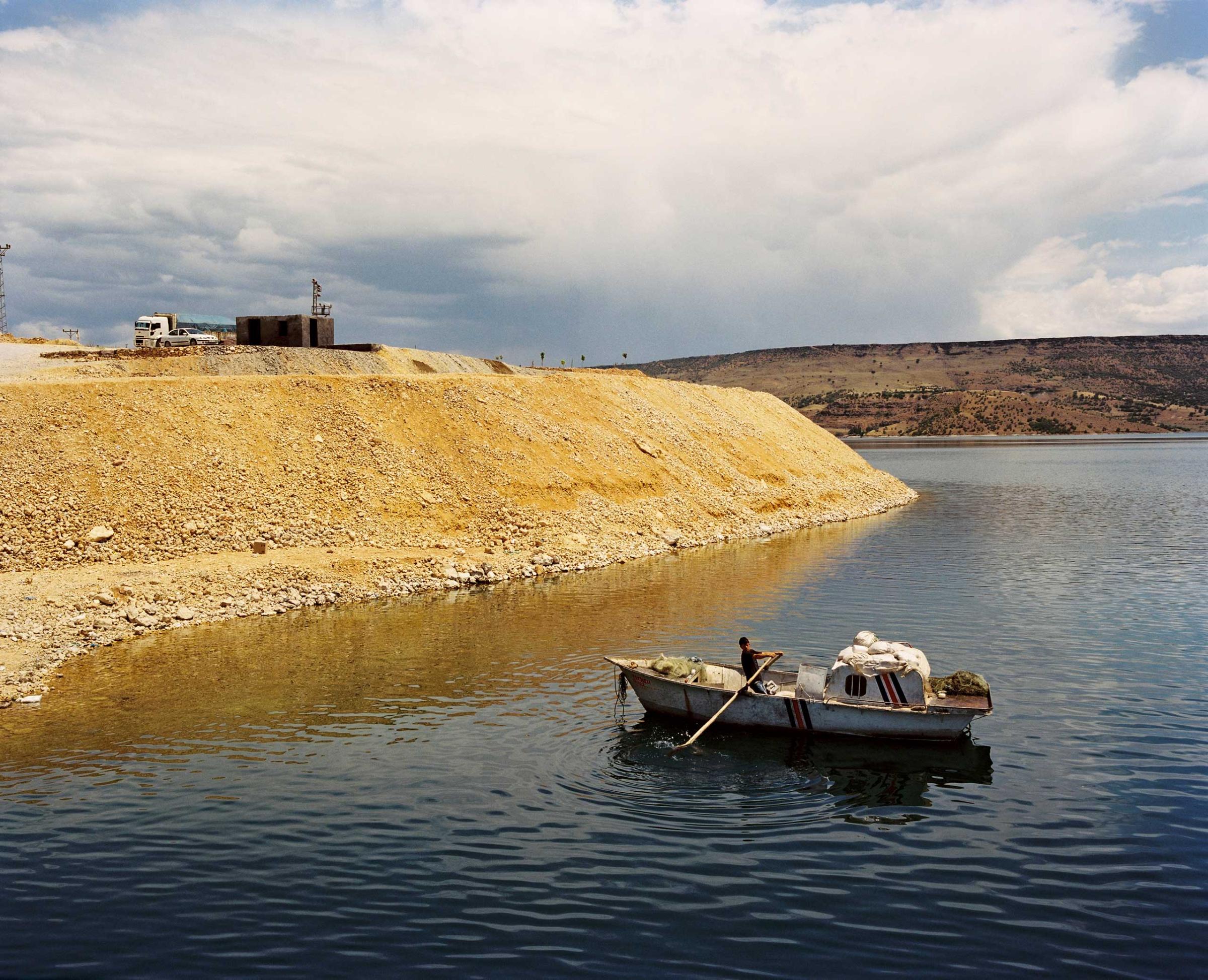 A man paddles in a boat across the Euphrates River near the hydroelectric Keban Dam. Turkey.