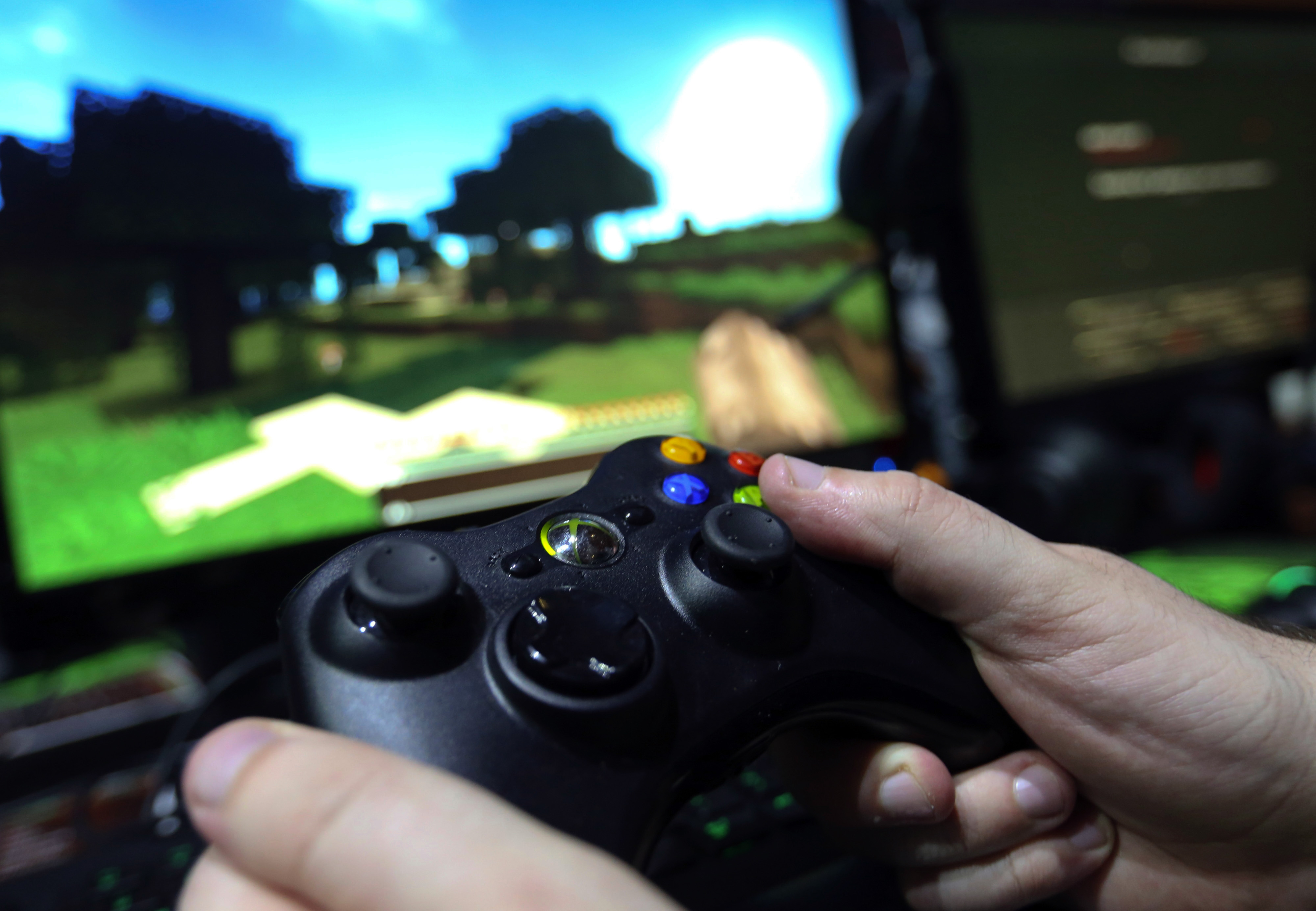 A visitor holds a hand control unit as he plays the Minecraft computer came, produced by Mojang AB, on a Microsoft Corp. Xbox One games consoles during the EGX gaming conference at Earls Court in London, U.K., on Sept. 25, 2014. (Bloomberg via Getty Images)
