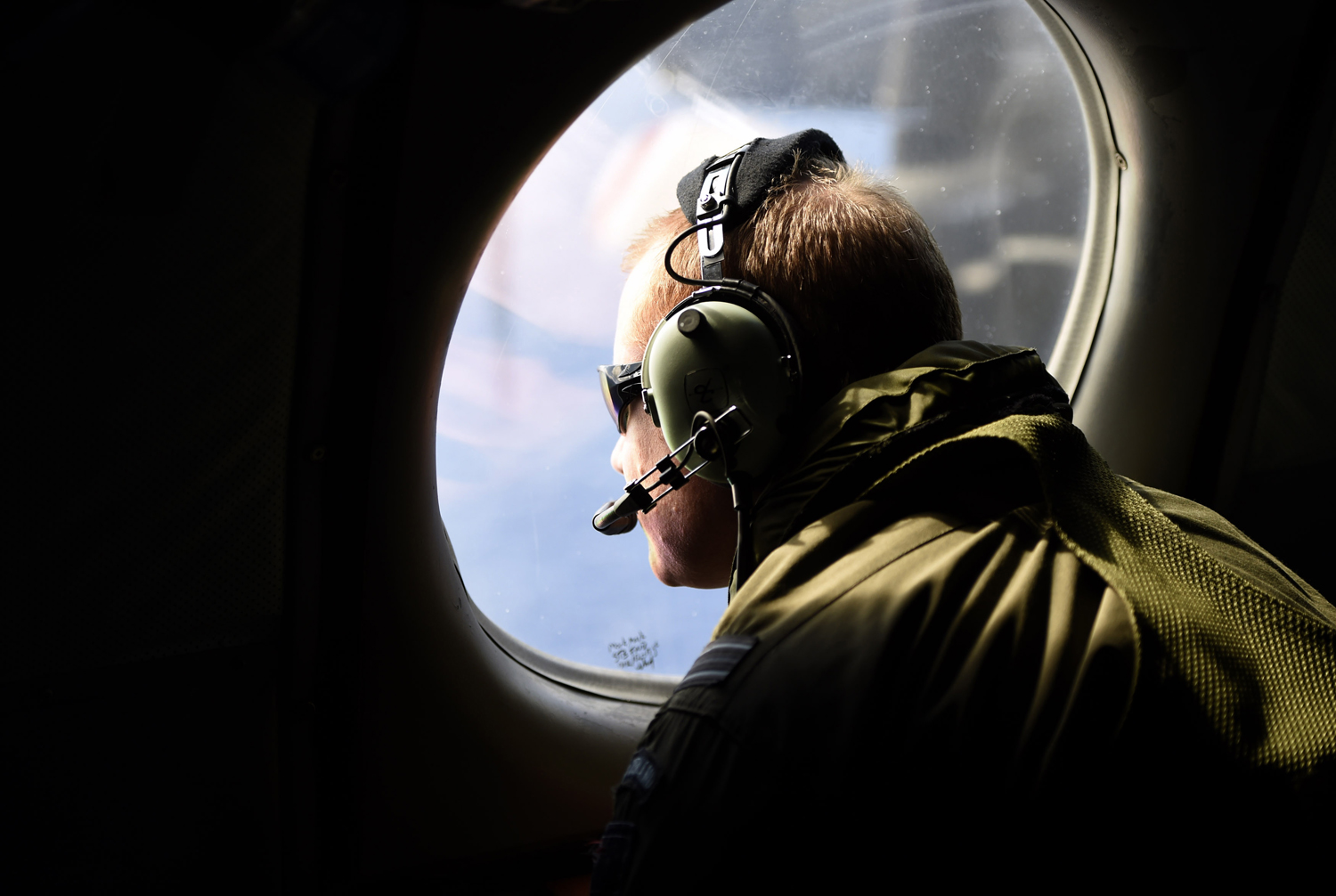 A crew member looks out an observation window aboard a Royal New Zealand Air Force (RNZAF) P3 Orion maritime search aircraft as it flies over the southern Indian Ocean looking for debris from missing Malaysian Airlines flight MH370