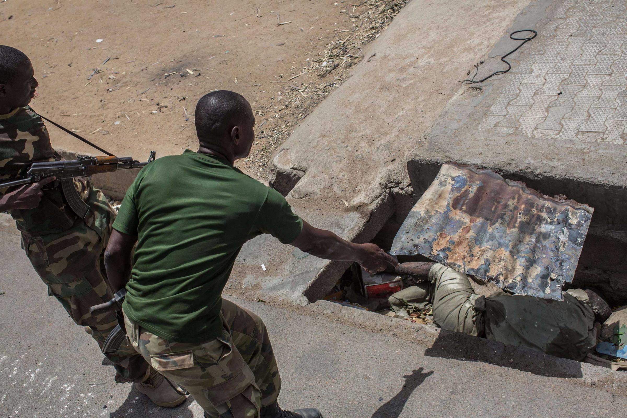 Members of the Nigerian army discover a body decomposing in a sewer in Bama on March 25, 2015.
