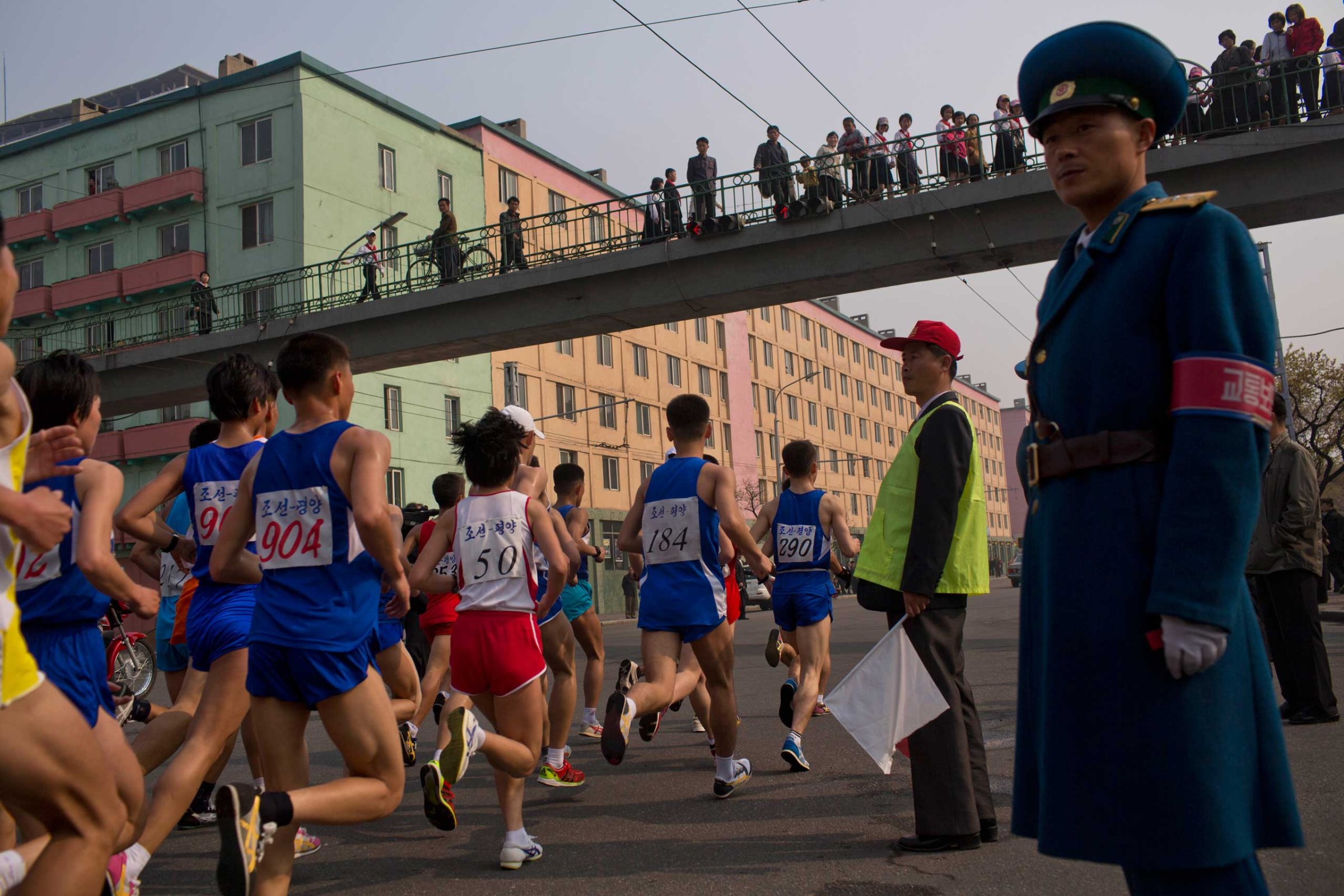 Runners pass under a pedestrian bridge during the running of the Mangyongdae Prize International Marathon in Pyongyang, North Korea on April 13, 2014.