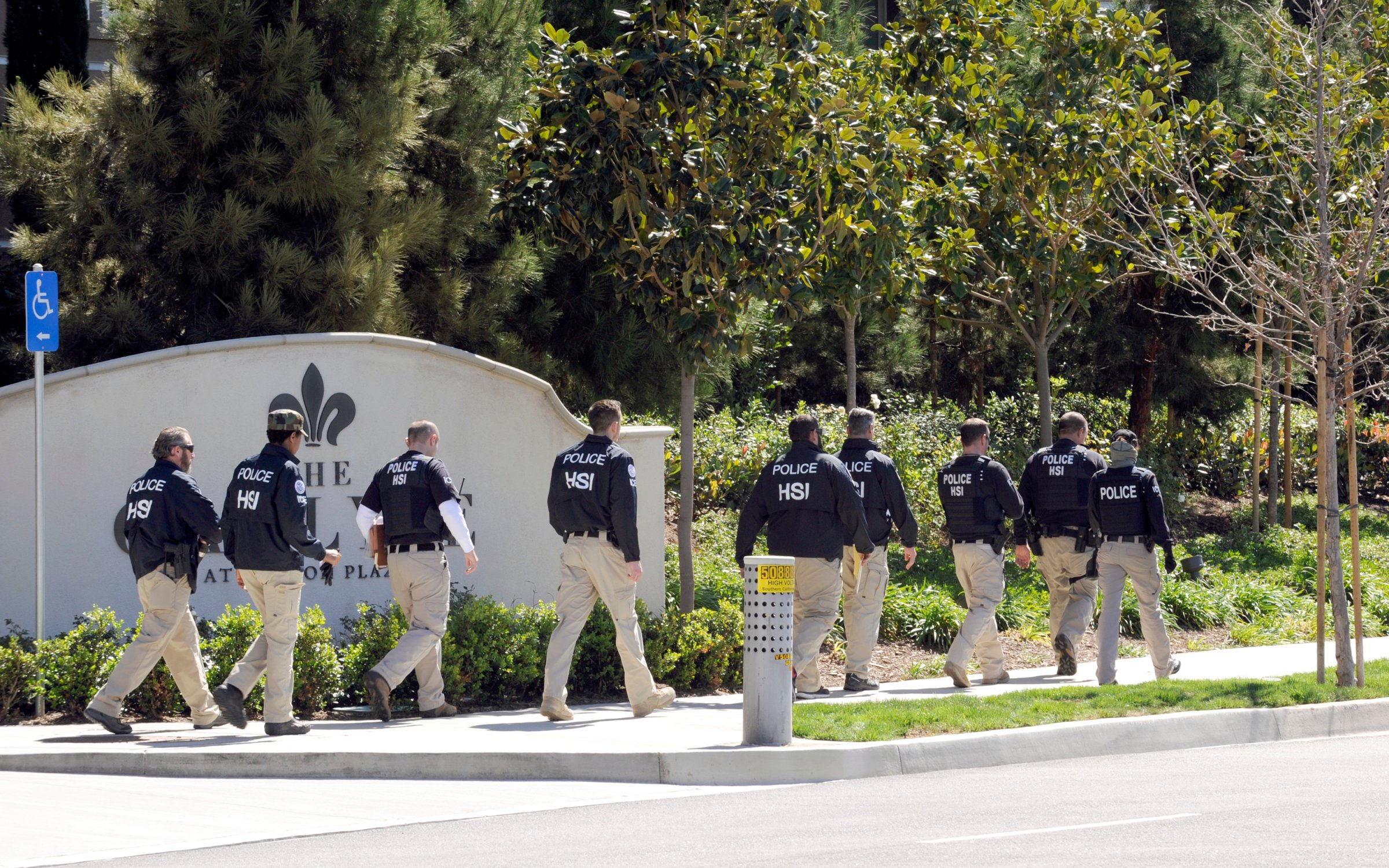 Federal agents walk past the Carlyle Apartments, the location of a suspected "baby tourism operation," in Irvine, Calif. on March 3, 2015.