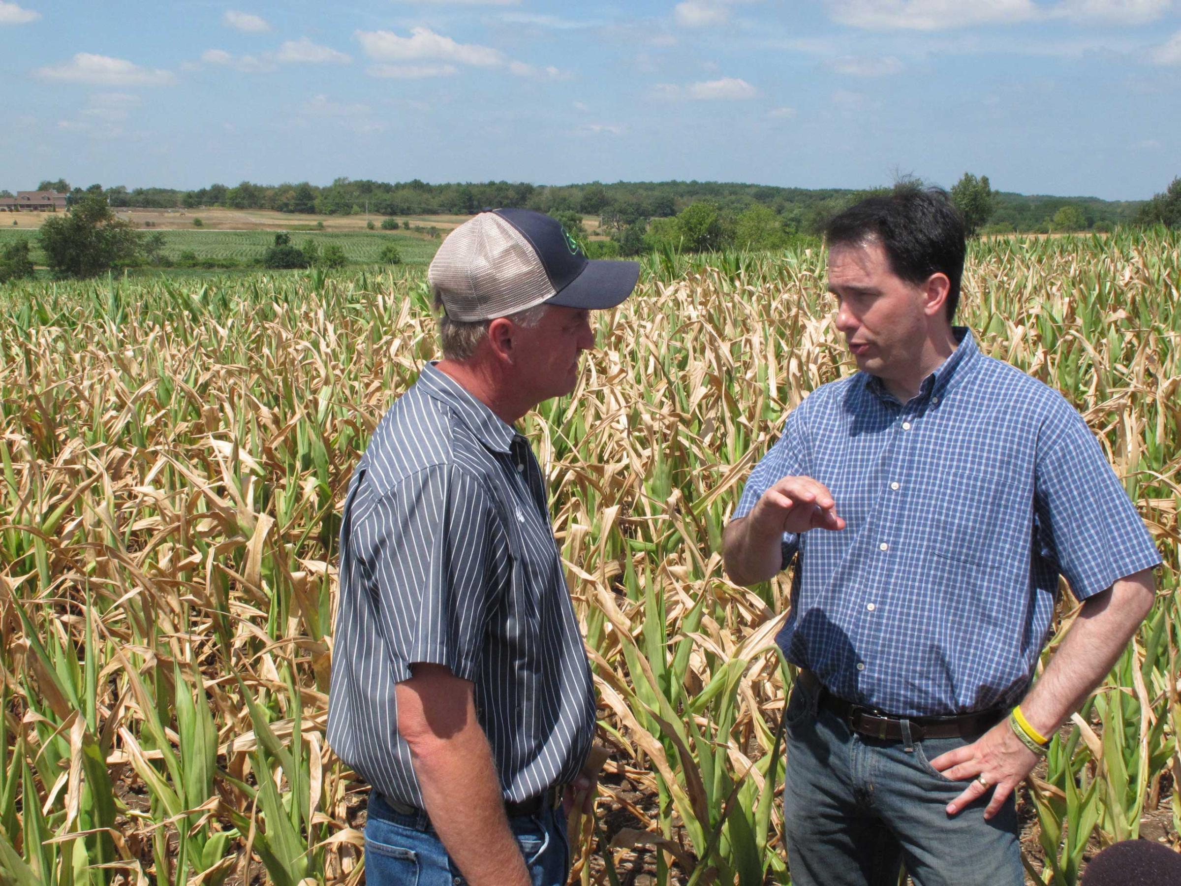 Gov. Scott Walker, right, talks with farmer Jeff Ehrhart about drought damage to his corn crop in the background in Burlington, Wis., on July 20, 2012.