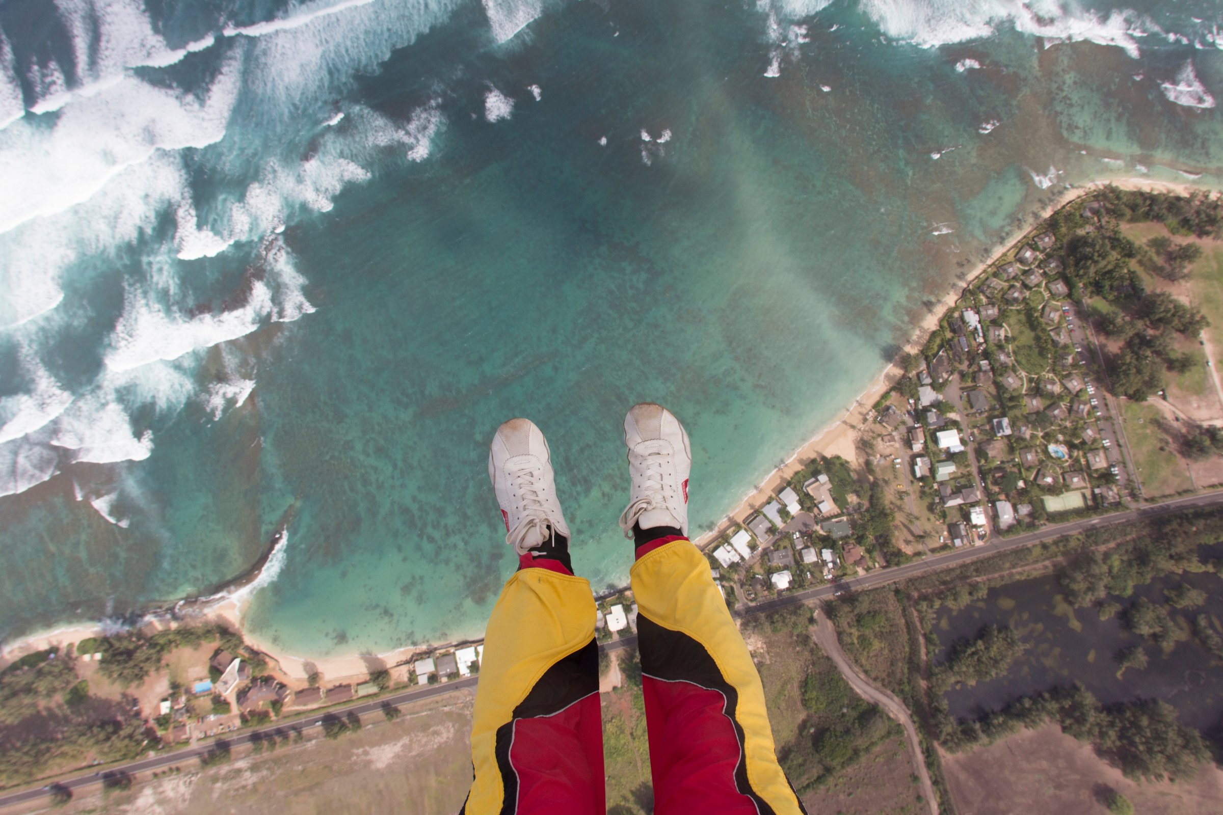 Legs and feet of skydiver above coastline