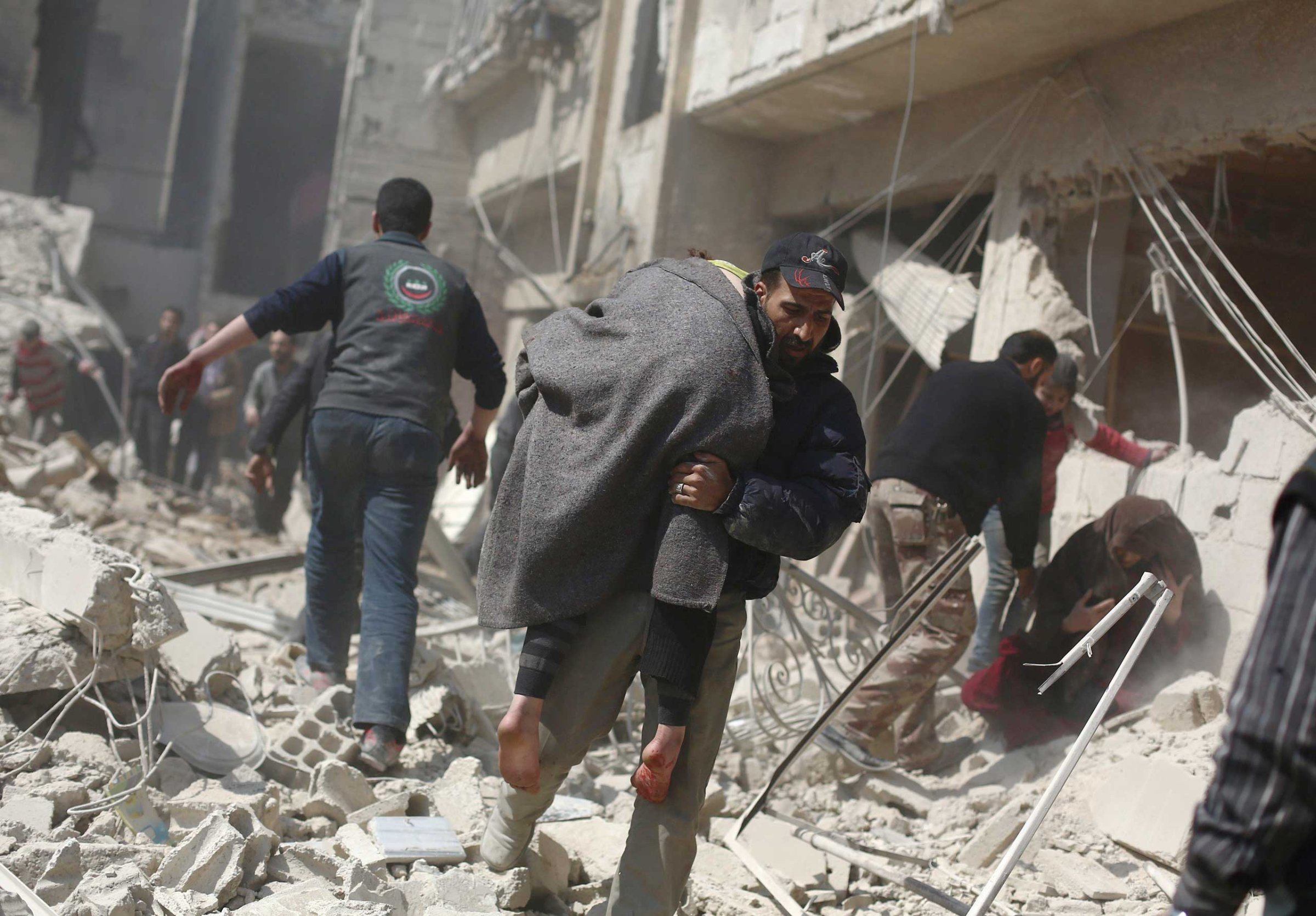 A man carries a wounded person in the rebel-held area of Douma, east of the Syrian capital Damascus, following reported air strikes by regime forces on March 15, 2015.