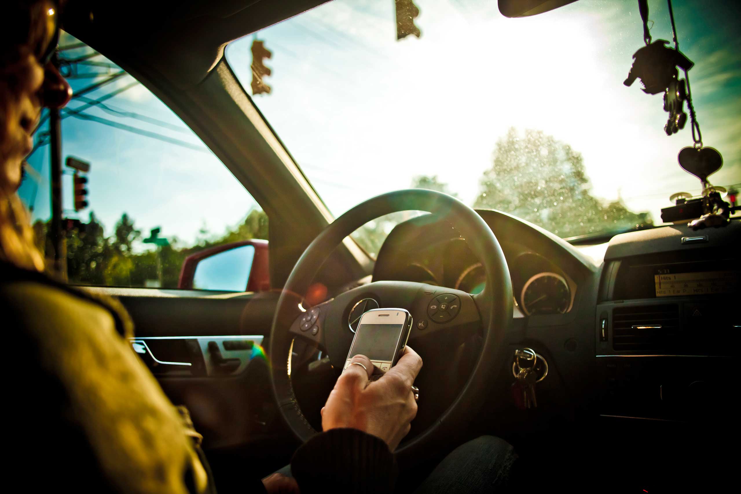 A stock image of a woman texting while driving a car