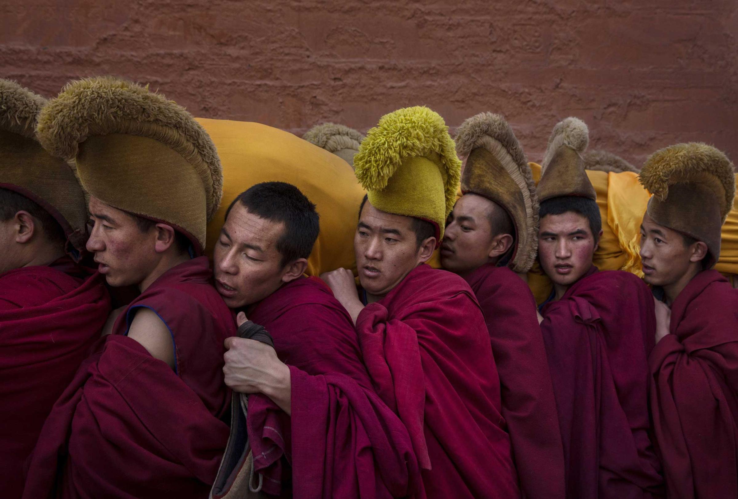 Tibetan Buddhist Monks of the Gelug, or Yellow Hat order, carry a large thangka of Buddha after showing it to worshippers during Monlam or the Great Prayer rituals on March 3, 2015 at the Labrang Monastery.