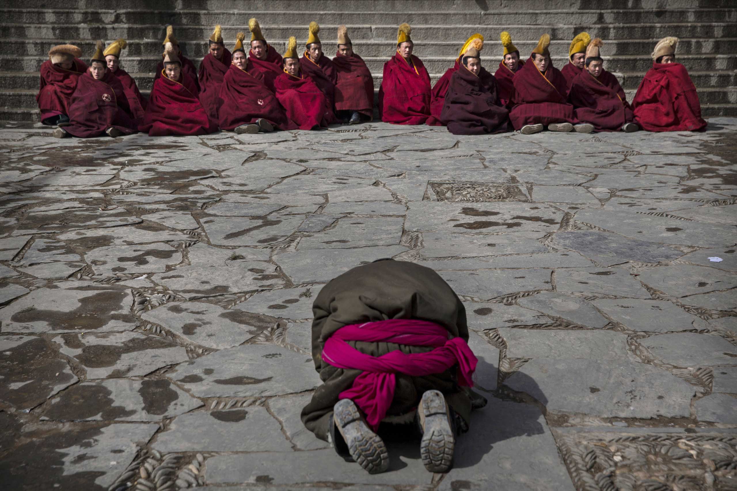 A worshipper prays in front of Tibetan Buddhist monks during Monlam or the Great Prayer rituals on March 5, 2015 at the Labrang Monastery.