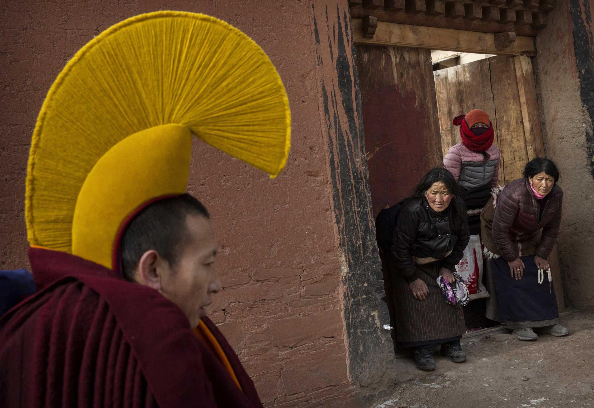 Devotees bow to a passingTibetan Buddhist monk on his way to take part in a special prayer during Monlam or the Great Prayer rituals on March 5, 2015 at the Labrang Monastery.