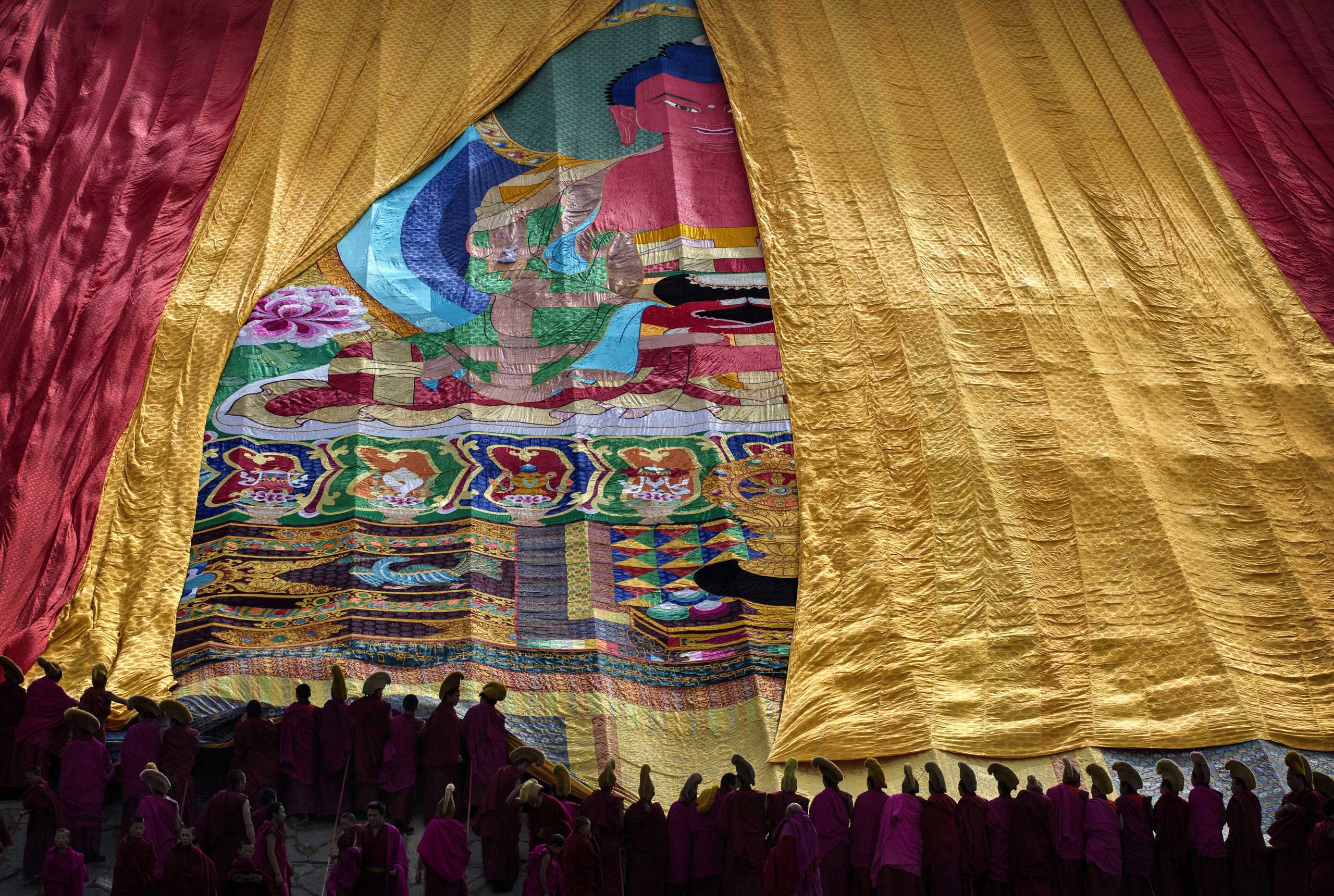 Tibetan Buddhist Monks of the Gelug, or Yellow Hat order, unveil a large thangka showing Buddha during Monlam or the Great Prayer rituals on March 3, 2015 at the Labrang Monastery.