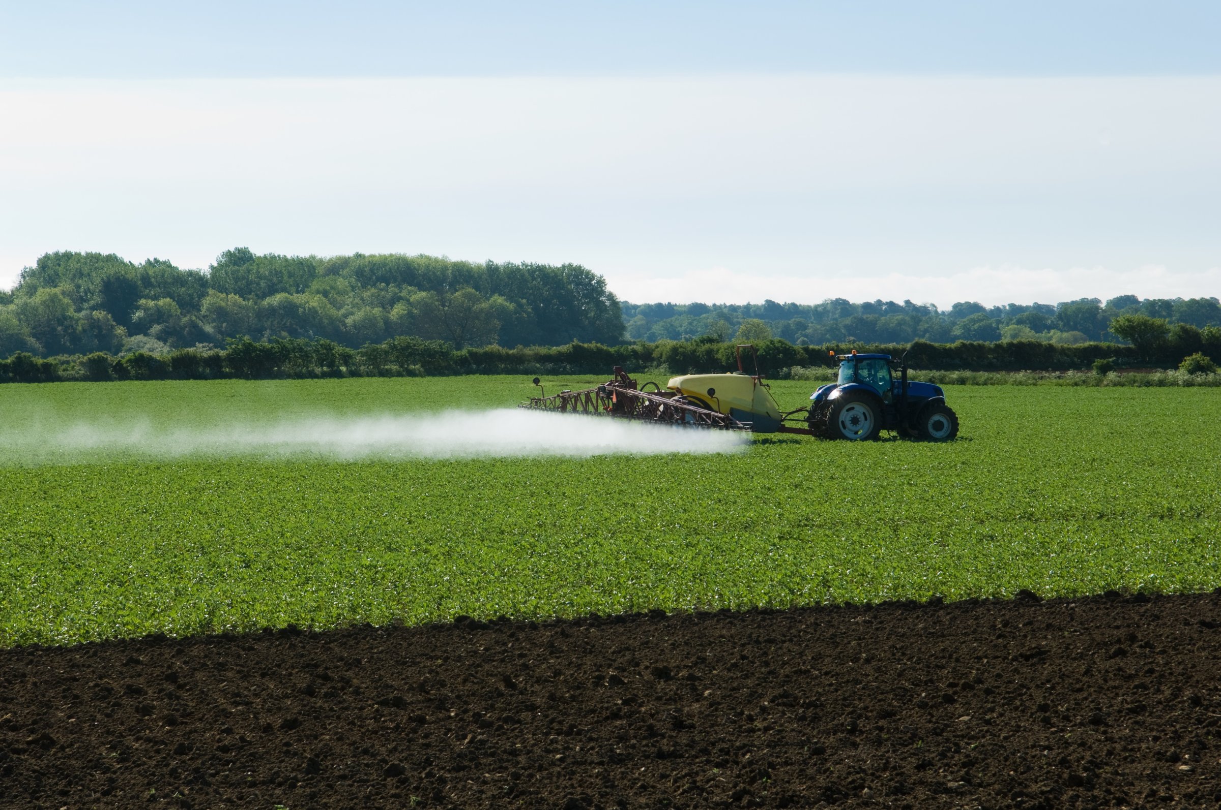 Tractor and crop sprayer spraying in field