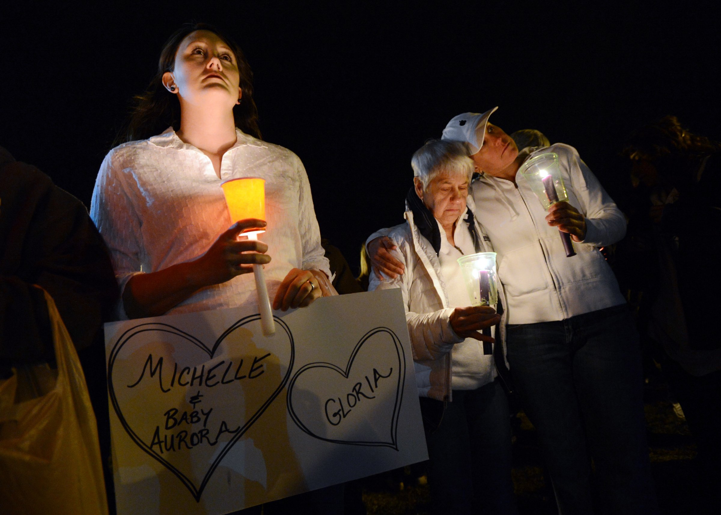 Cheryl Swanson, left, Elaine Derstine, and her daughter, Michelle Smith, are part of a moment of silence during the vigil.