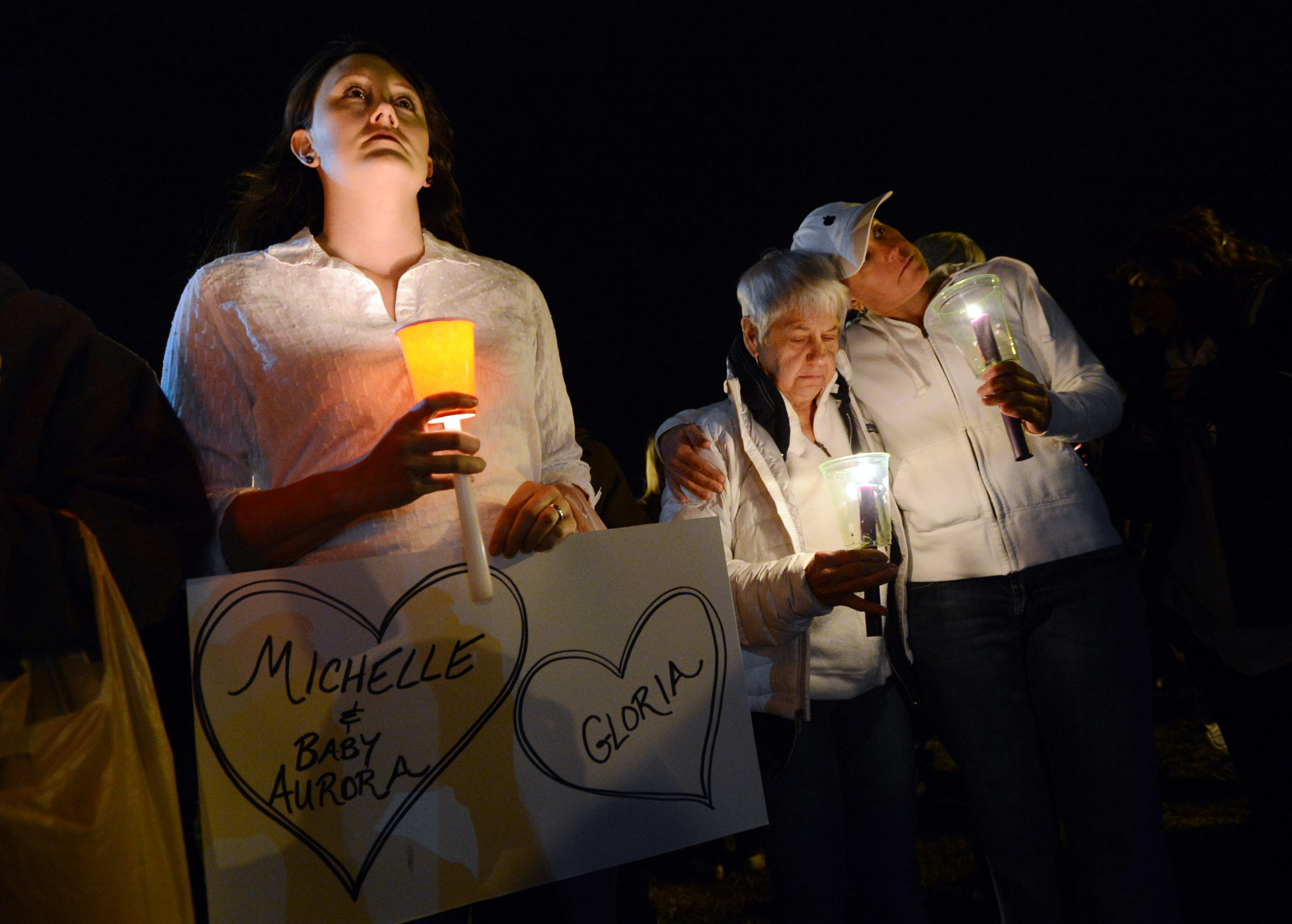 Cheryl Swanson, left, Elaine Derstine, and her daughter, Michelle Smith, are part of a moment of silence during the vigil. (Cliffv Grassmick—AP)
