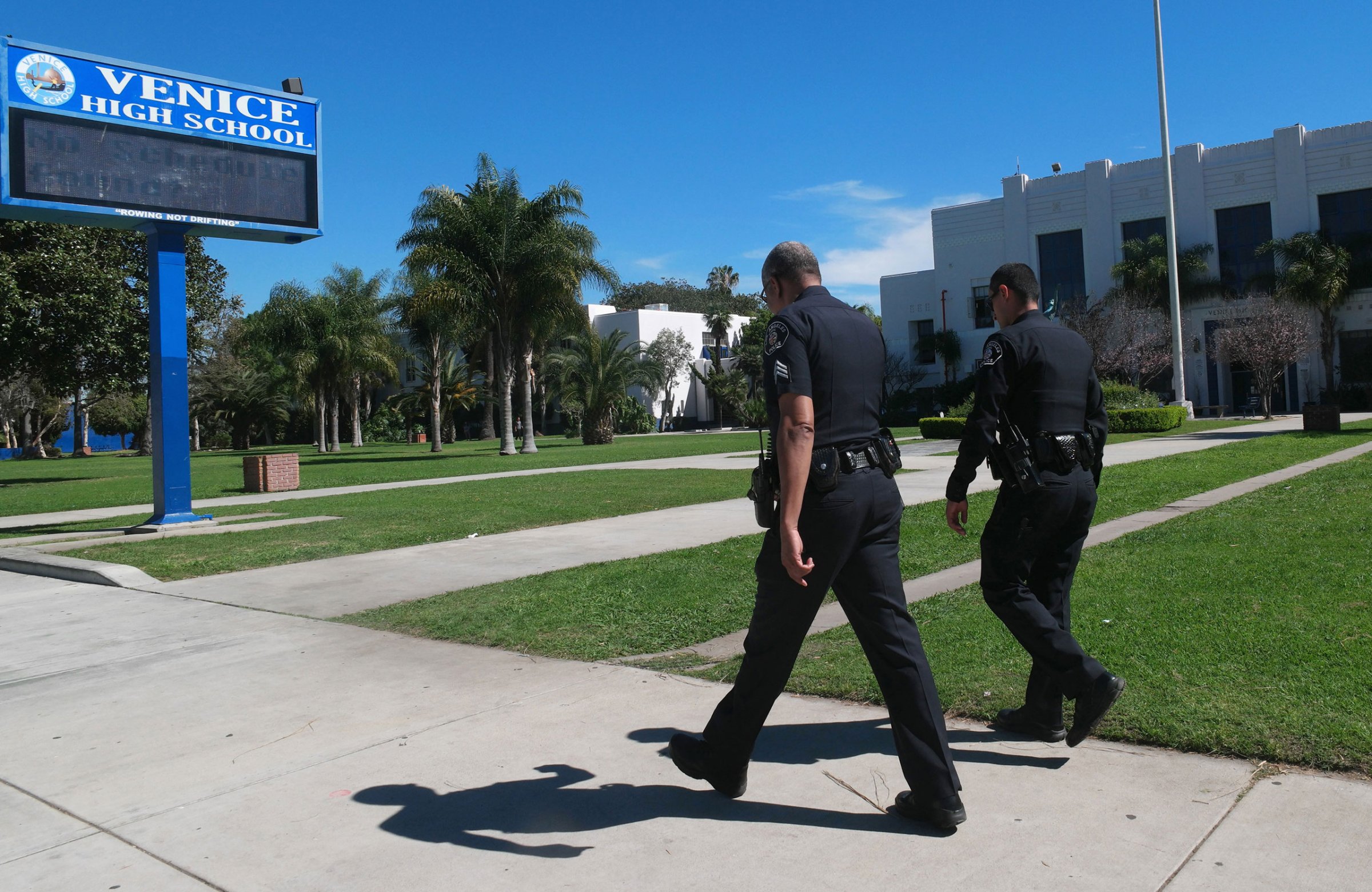 Police officers walk in front of Venice High School where they are investigating allegations of sexual assault in Los Angeles