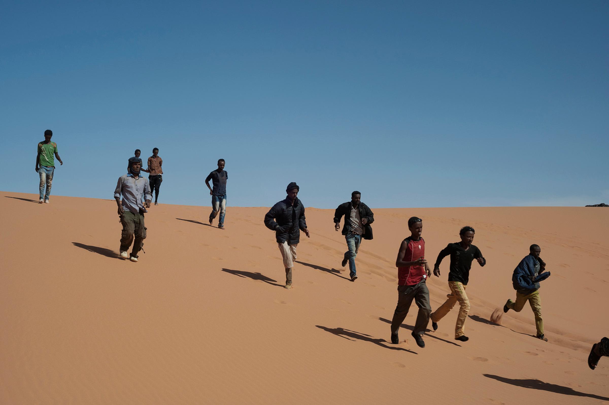 Refugees run to reach their transport to continue their journey in Libya, near the border with Egypt, May 18, 2014.