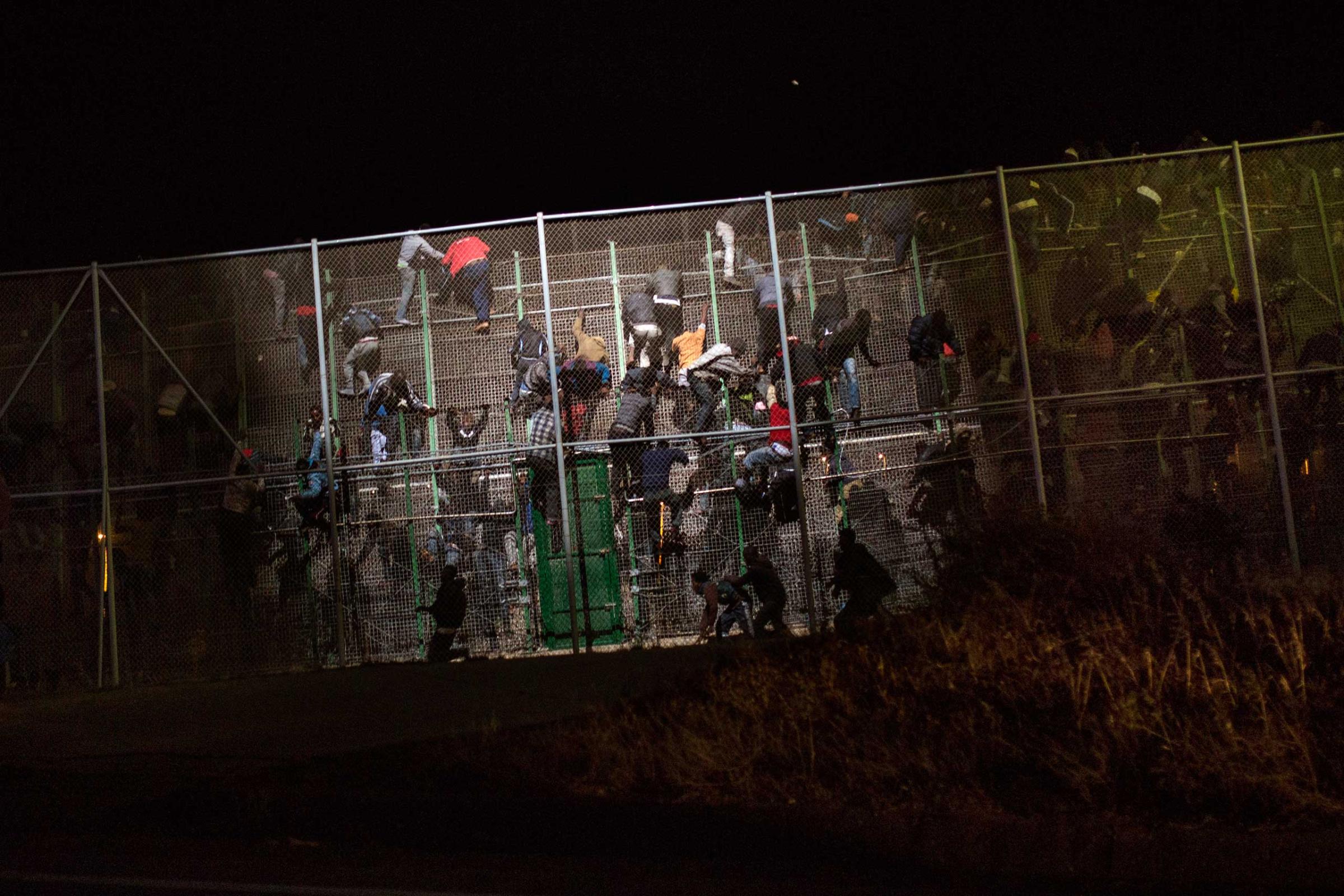 Sub-Saharan migrants scale a metallic fence that divides Morocco and the Spanish enclave of Melilla on May 28, 2014.