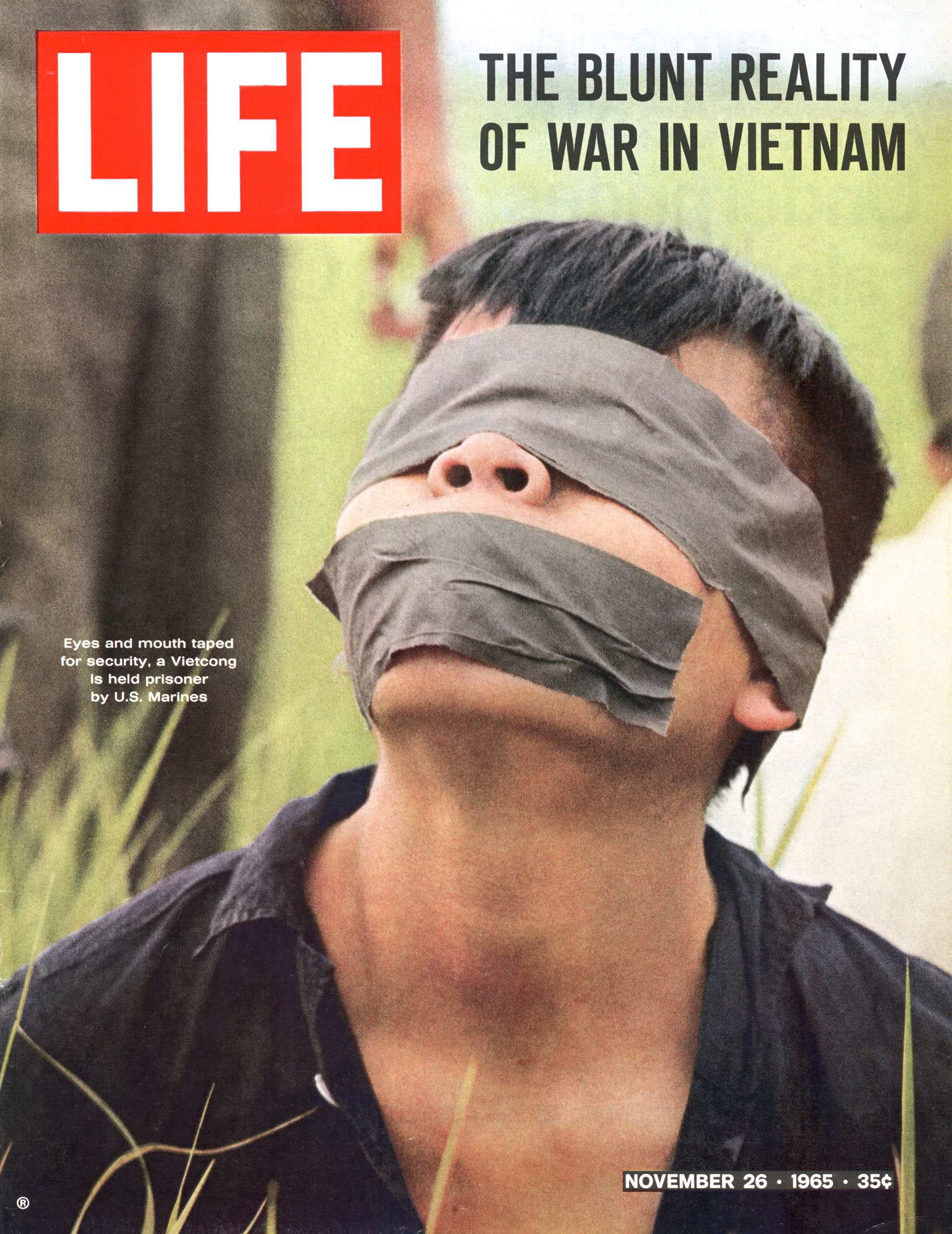 Eyes and mouth taped for security, a Vietcong is held prisoner by U.S. Marines.