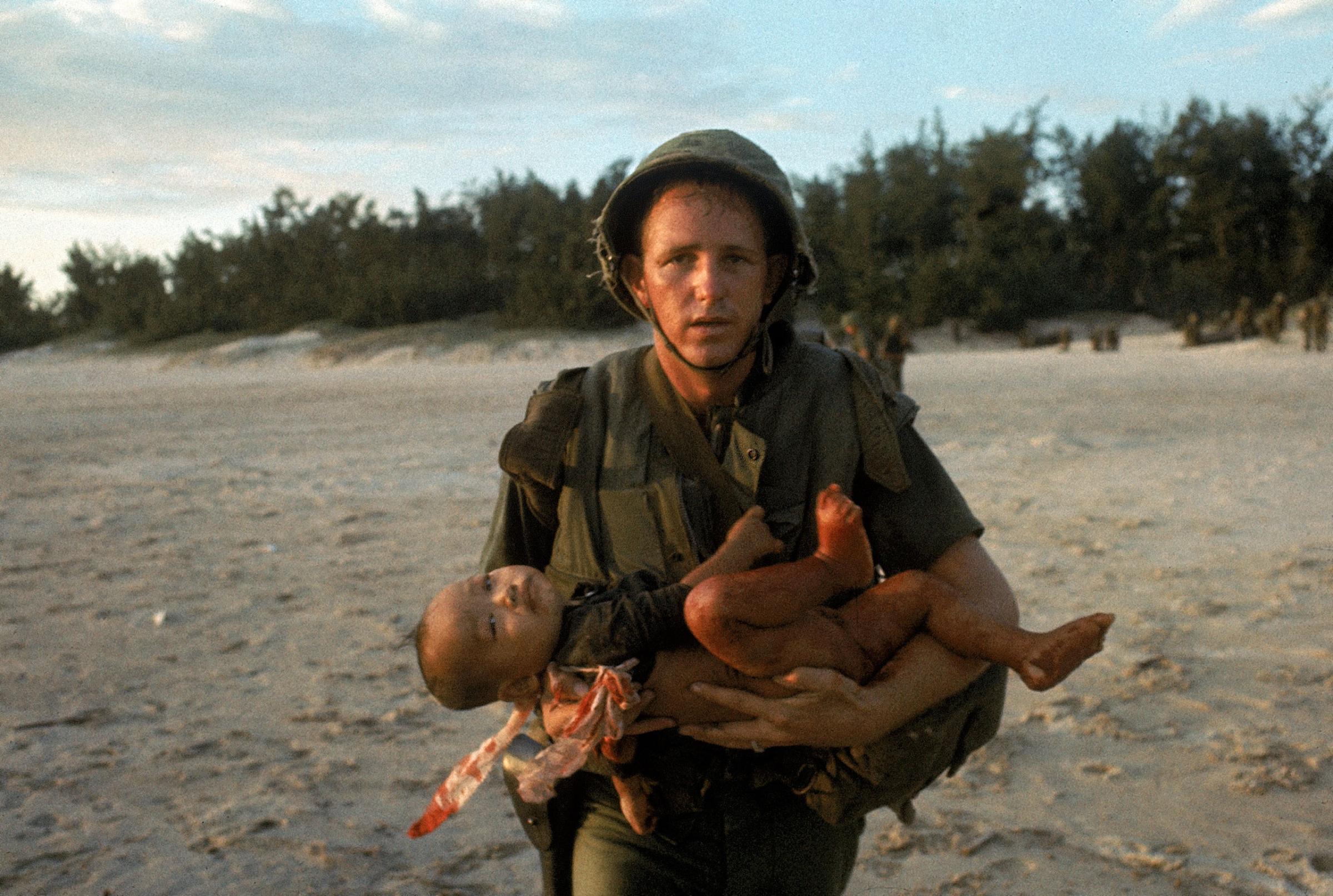 US Marine holding an injured Vietnamese child.