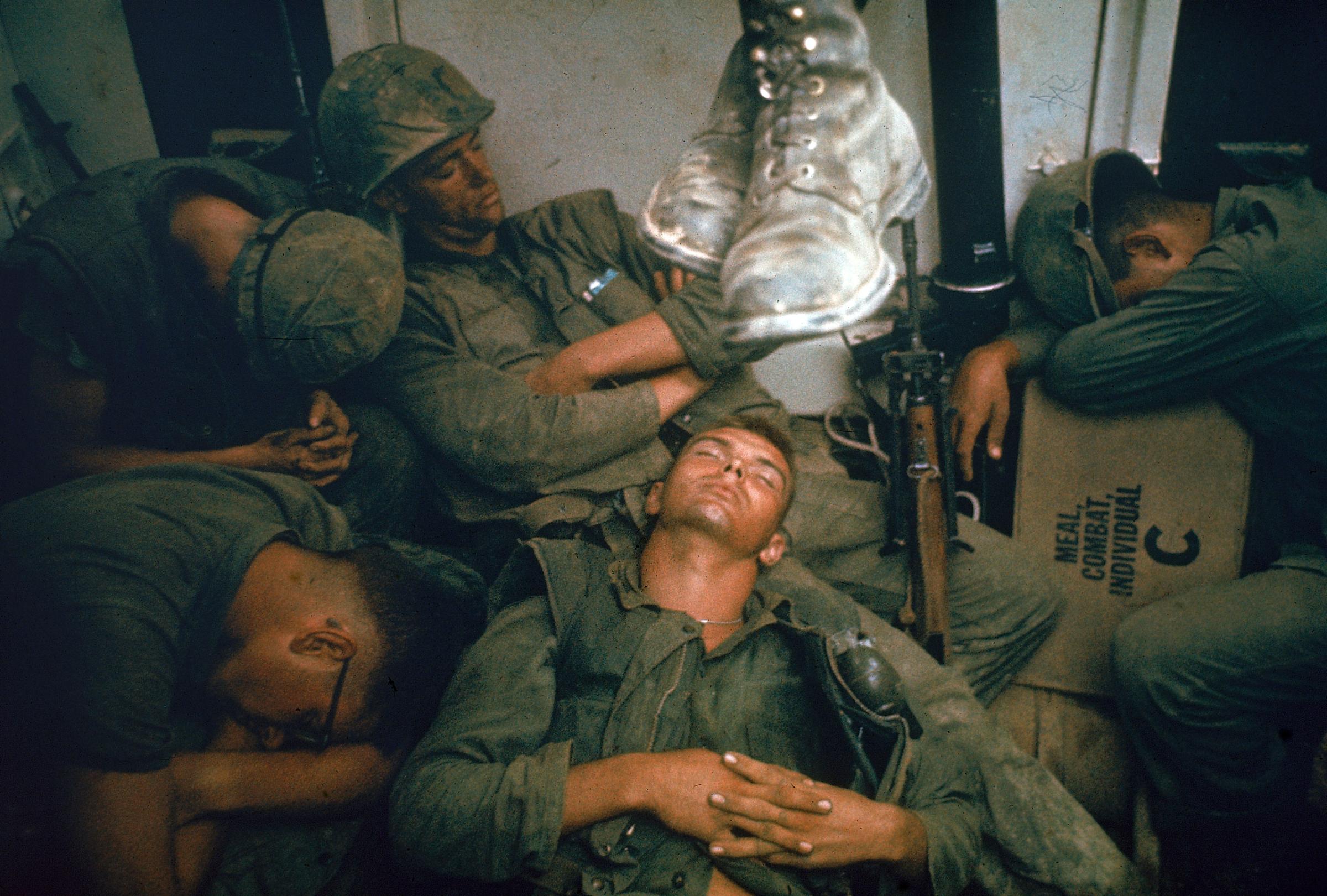 Bone-weary troops flake out in an Amtrak after the beachhead is secured. Marines fought from dawn until dark in temperatures up to 130 degrees on just two canteens of water per man.