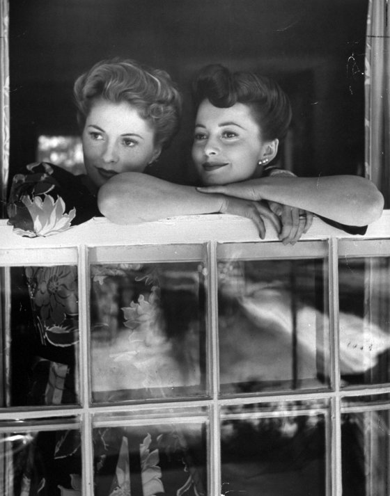 As successful movie stars, Joan (left) and Olivia make one of their rare appearances together in a window at Joan's home. This year they were winner and runner-up, respectively, for the Academy Award.