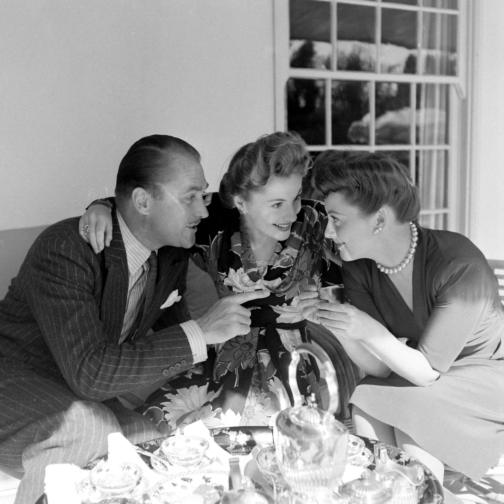 On the back terrace of their white Georgian home in Beverly Hills, Joan and her husband, Actor Brian Aherne, chat with Olivia. The Ahernes are extremely happy and domestic, like to have tea each afternoon at 4, to dress for dinner and have in Aherne's British friends. He is a licensed pilot and now helps in the West Coast Civil Air Patrol.