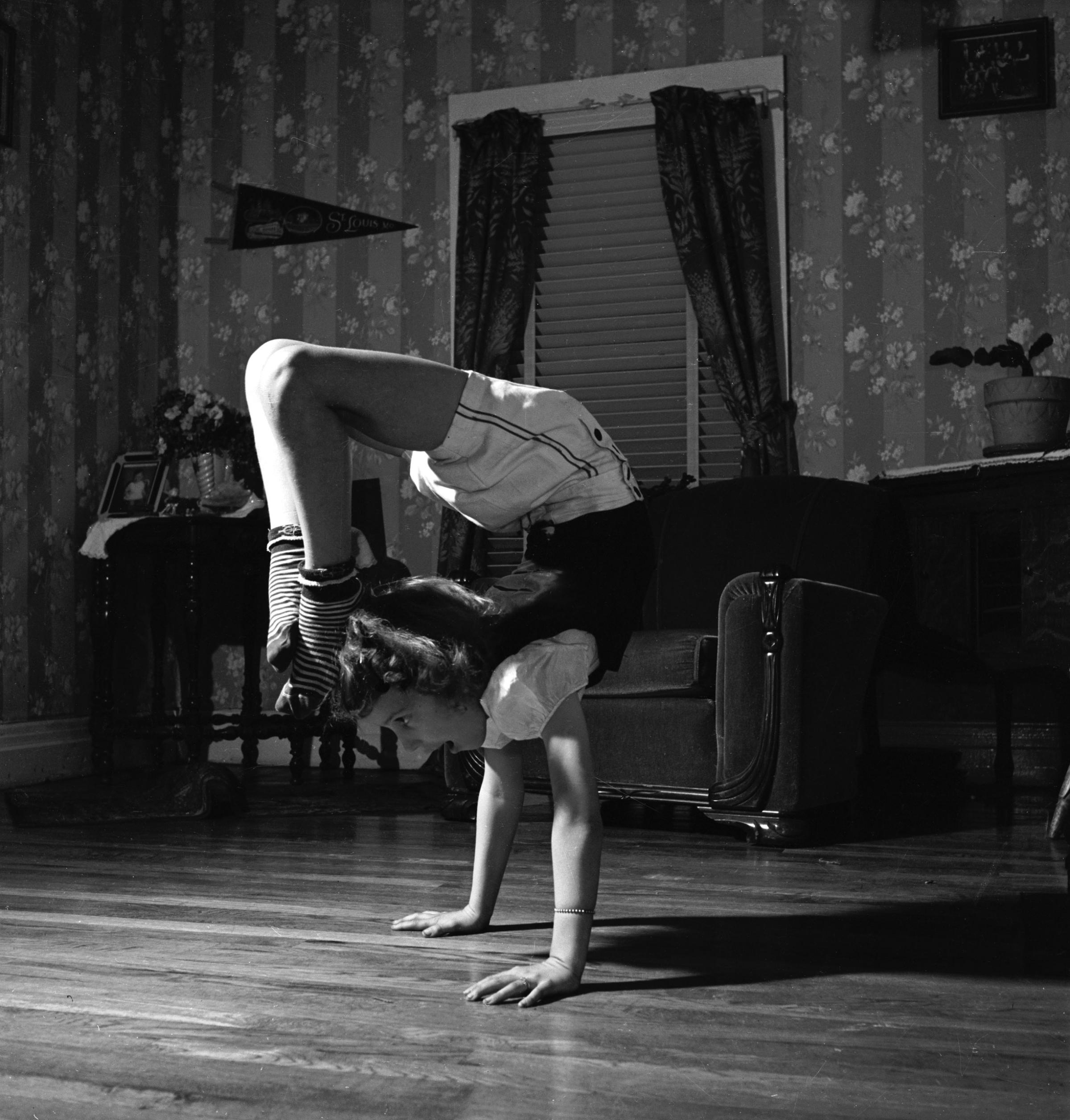 June Carter performing a hand stand in the living room of her family's home.