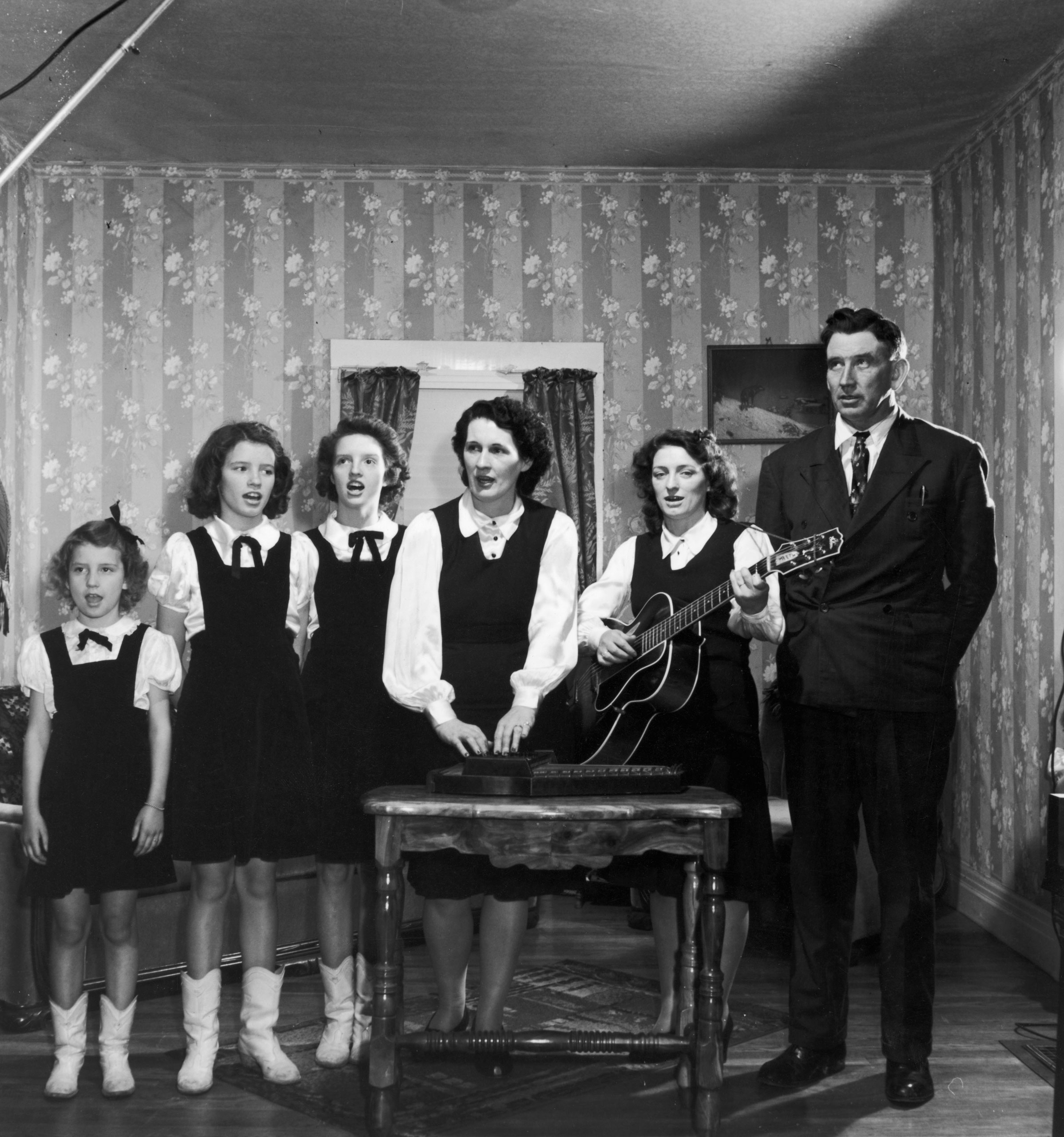 Portrait of the legendary Carter family (R-L) A. P. Carter, his sister-in-law Maybelle (playing guitar), her sister Sara (A.P.'s wife) playing autoharp and; Maybelle's young daughters Helen, June and; Anita; singing together home.