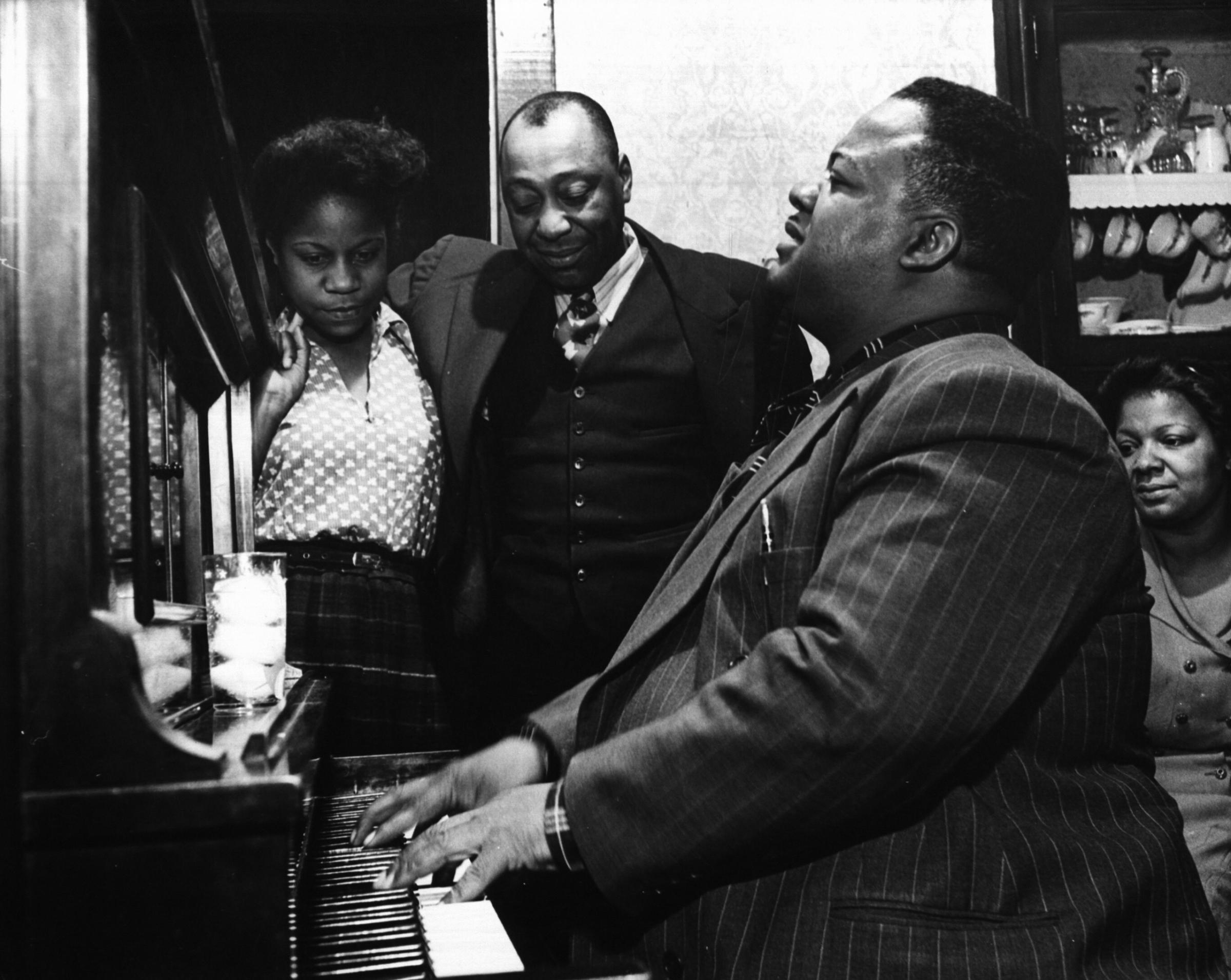 Meade Lux Lewis on the piano with Jimmy Yancey in the background performing in New Orleans, 1944.