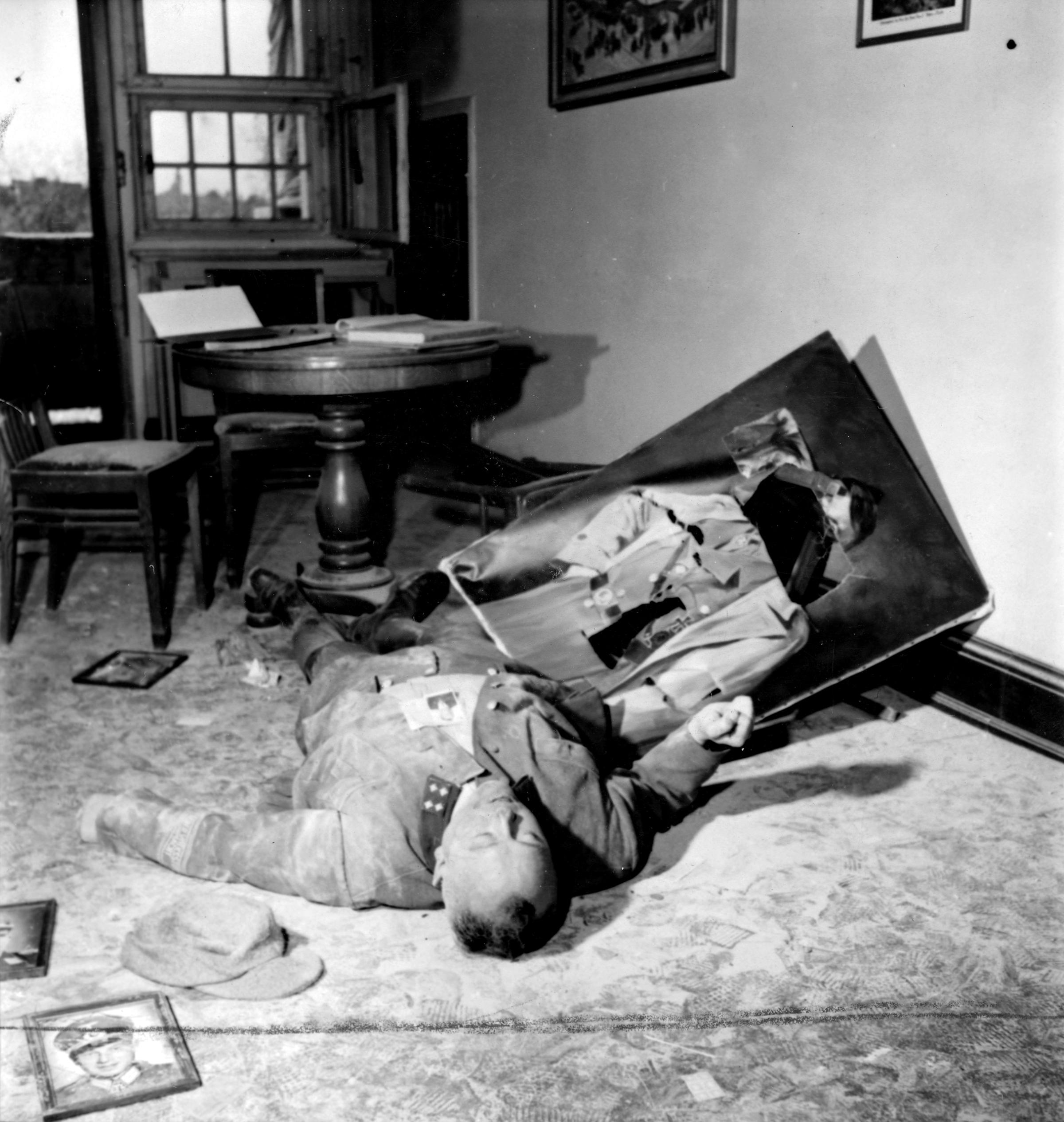 Commanding officer of City Volksturm lying dead next to a slashed picture of Hitler after committing suicide in small room at City Council Office after victorious American soldiers enter the city.