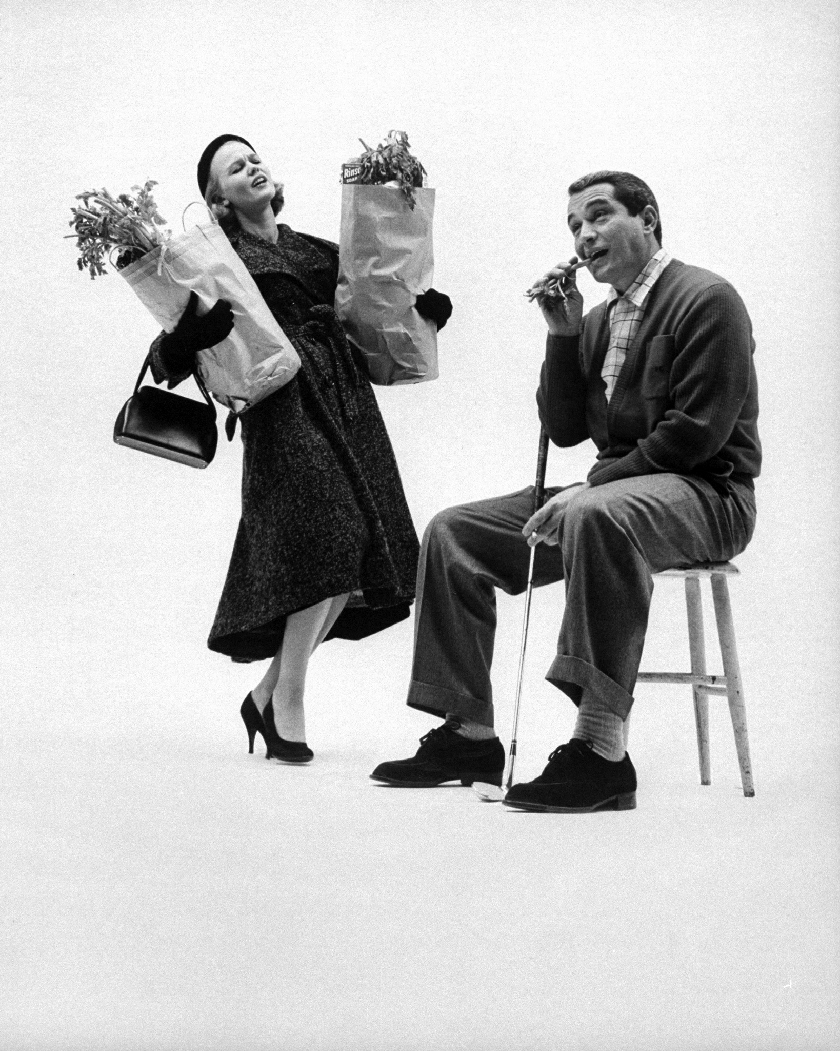 He must not be impolite. Acting out the part of a rude husband, which the girls polled do not want, Perry Como sits idly in chair ignoring the lady as she staggers by weighed down down by groceries. The poll also says that husbands must not be moody, jealous, secretive, arrogant.